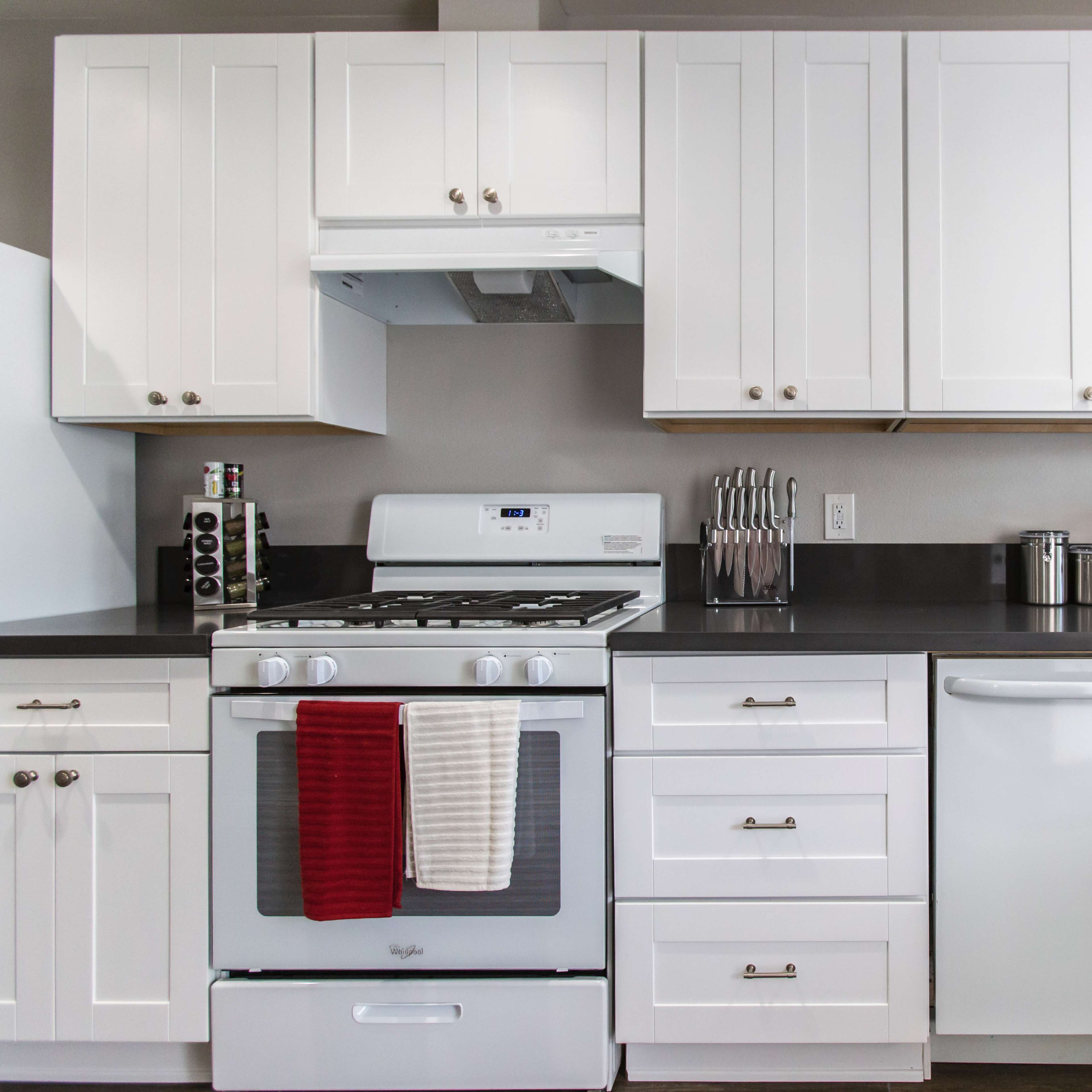 A modern kitchen with white cabinetry, a stainless steel stove, and a countertop appliance arrangement.