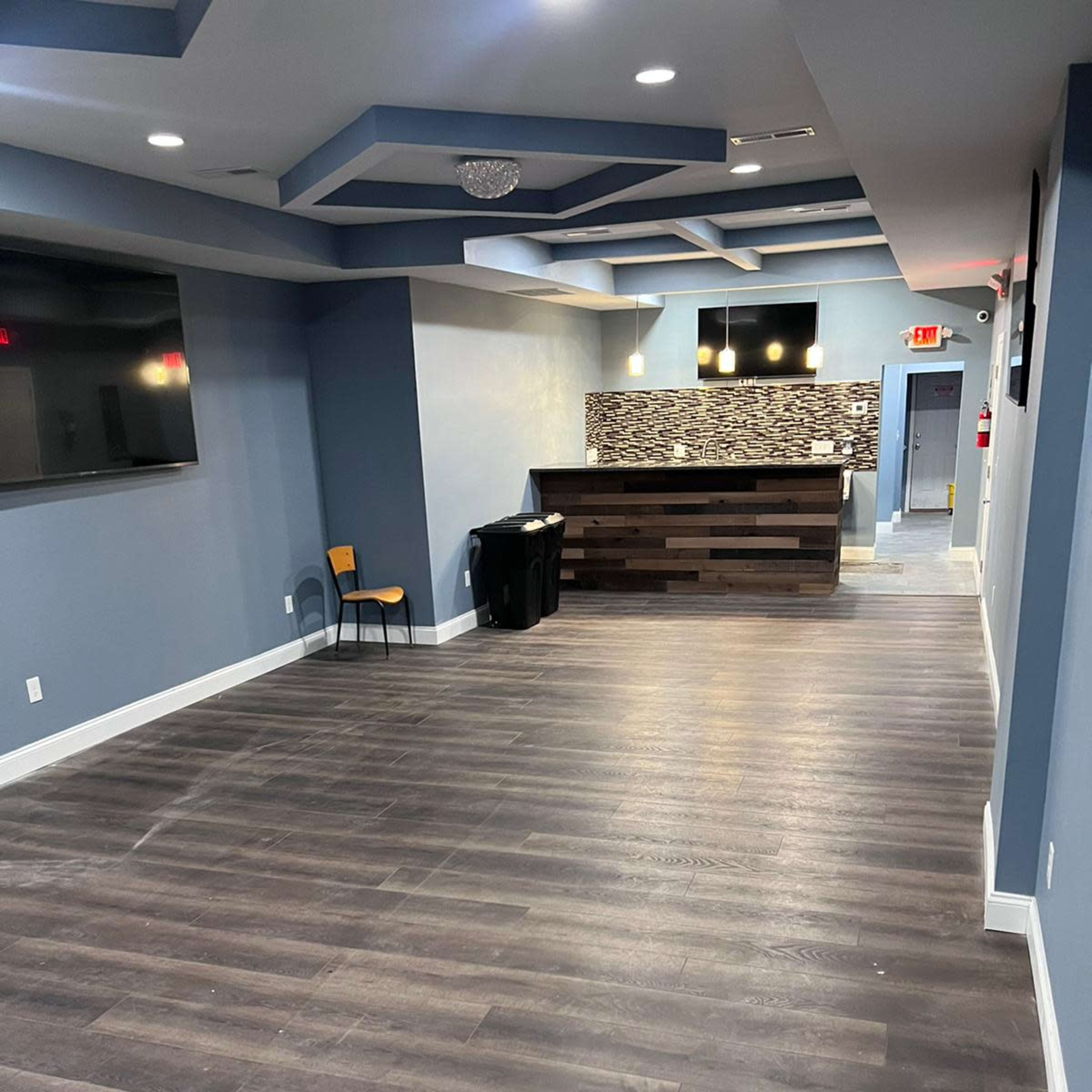 A spacious indoor area with a reception desk, a chair, and a flat-screen TV mounted on the wall.