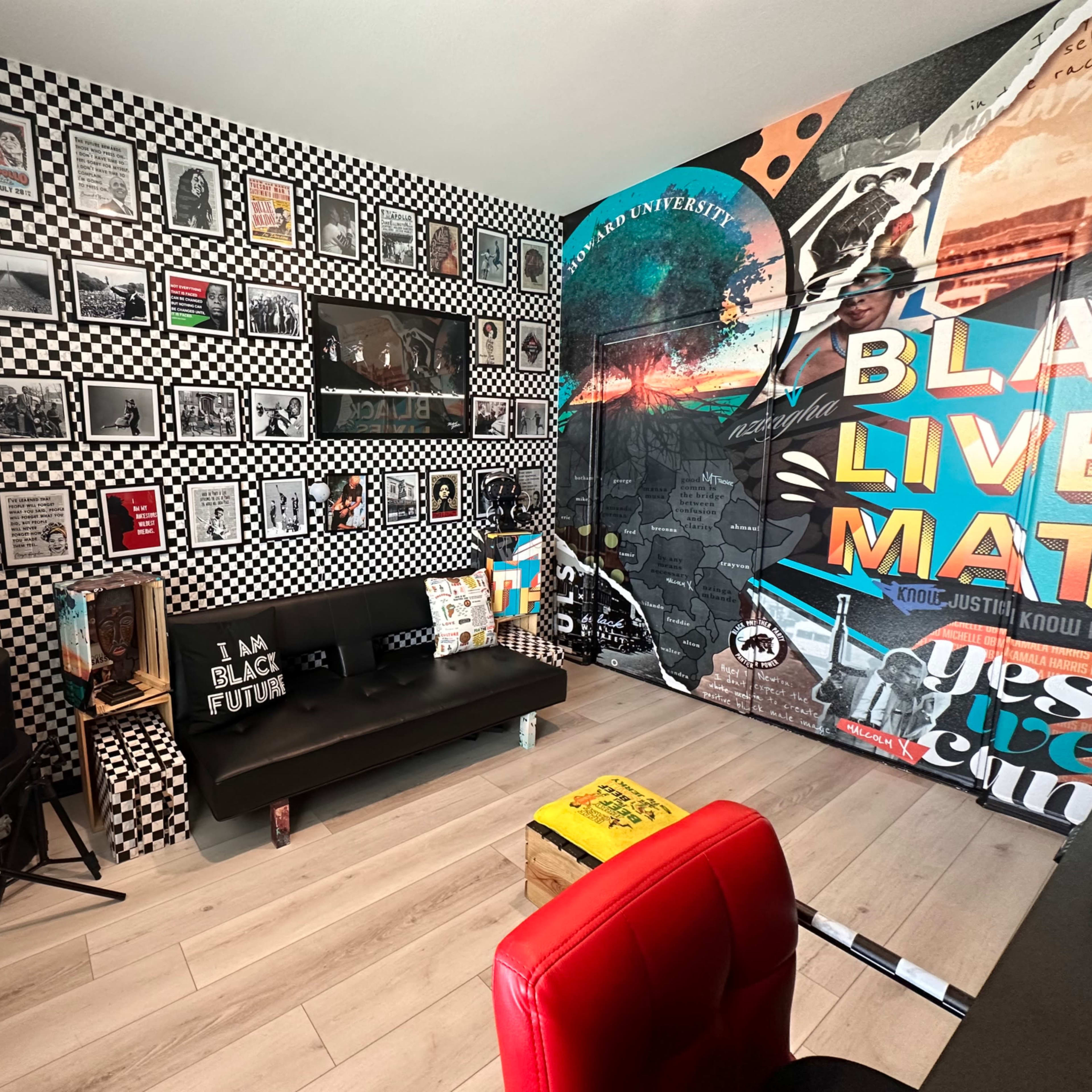The room features a black and white checkered wall design, adorned with various framed photographs, and a large mural with the phrases "BLACK LIVES MATTER" and "I AM BLACK FUTURE."