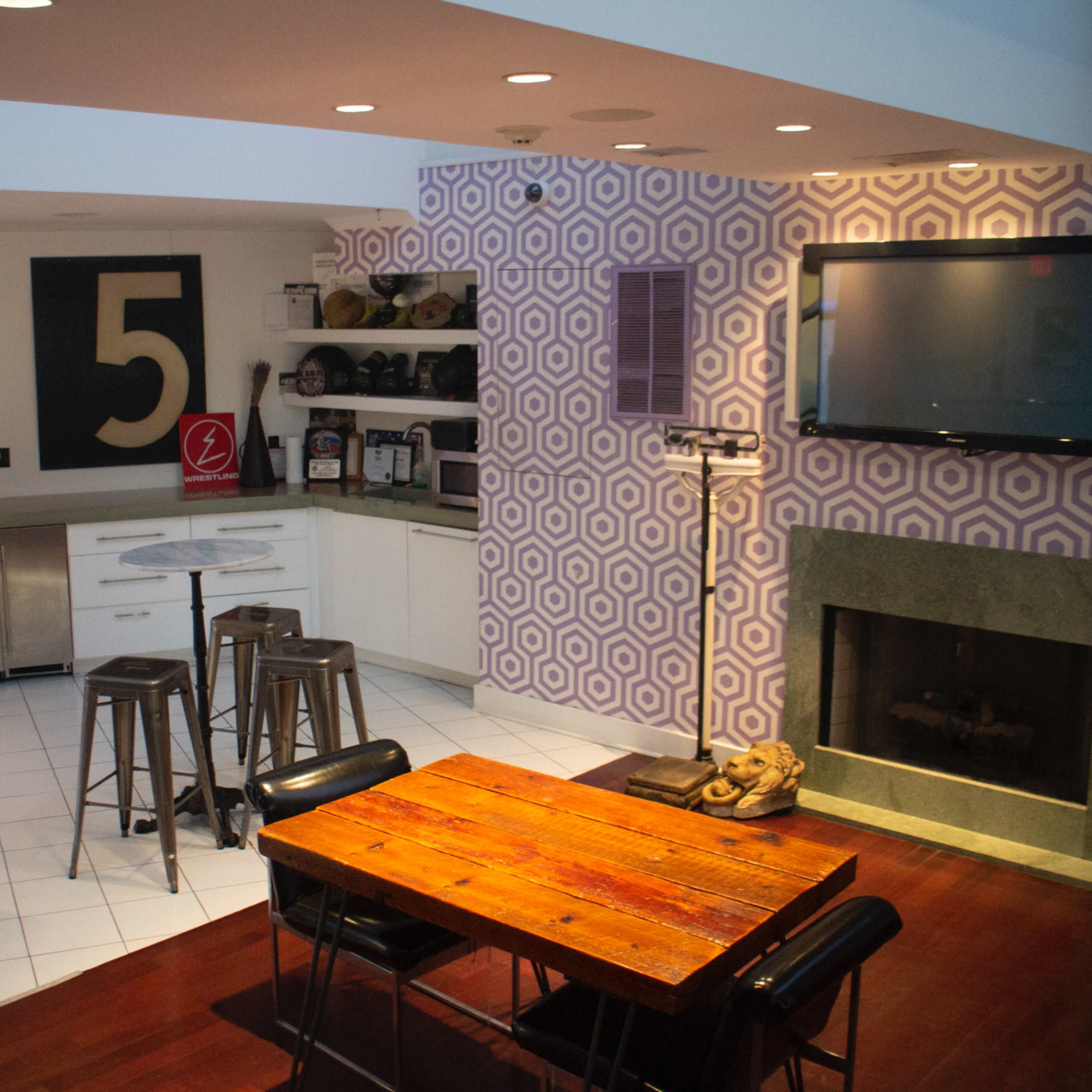 A modern kitchen and dining area featuring a pink refrigerator, a gas fireplace, and a patterned wall with a large number 5 displayed.