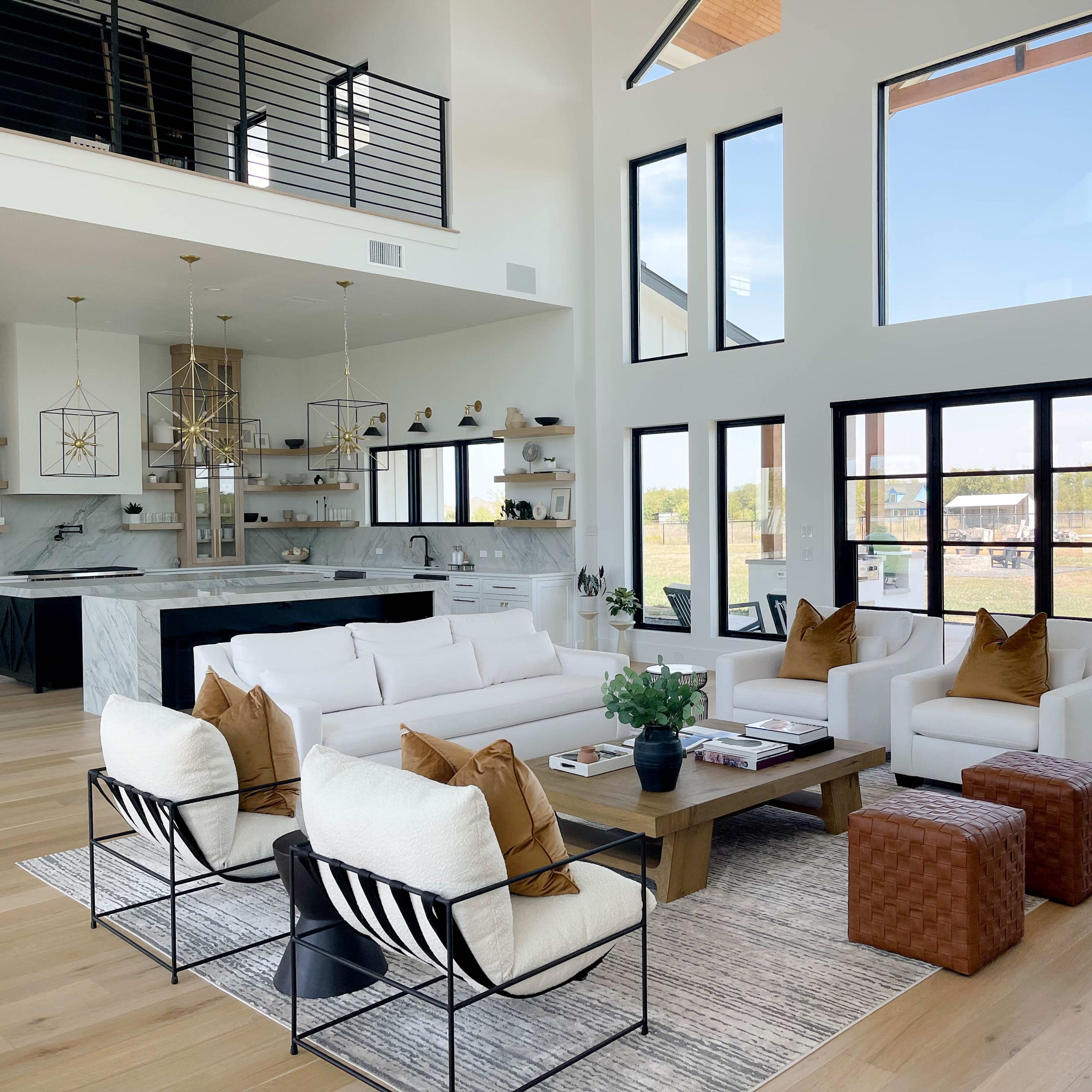 A spacious modern living room with a white sectional sofa, a wooden coffee table, and large windows that allow natural light to fill the space.