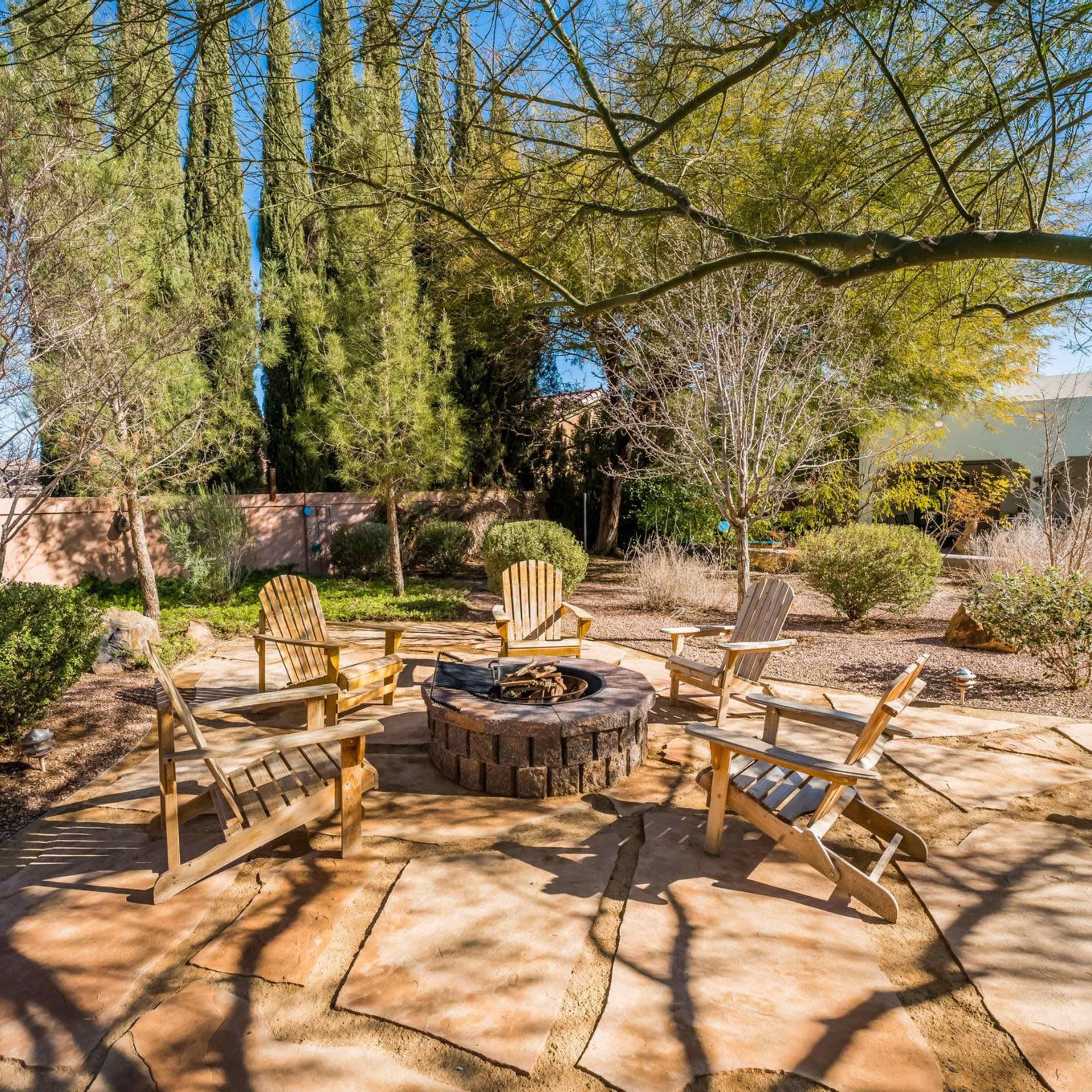 A curved swimming pool surrounded by desert landscaping and a covered patio with outdoor furniture.