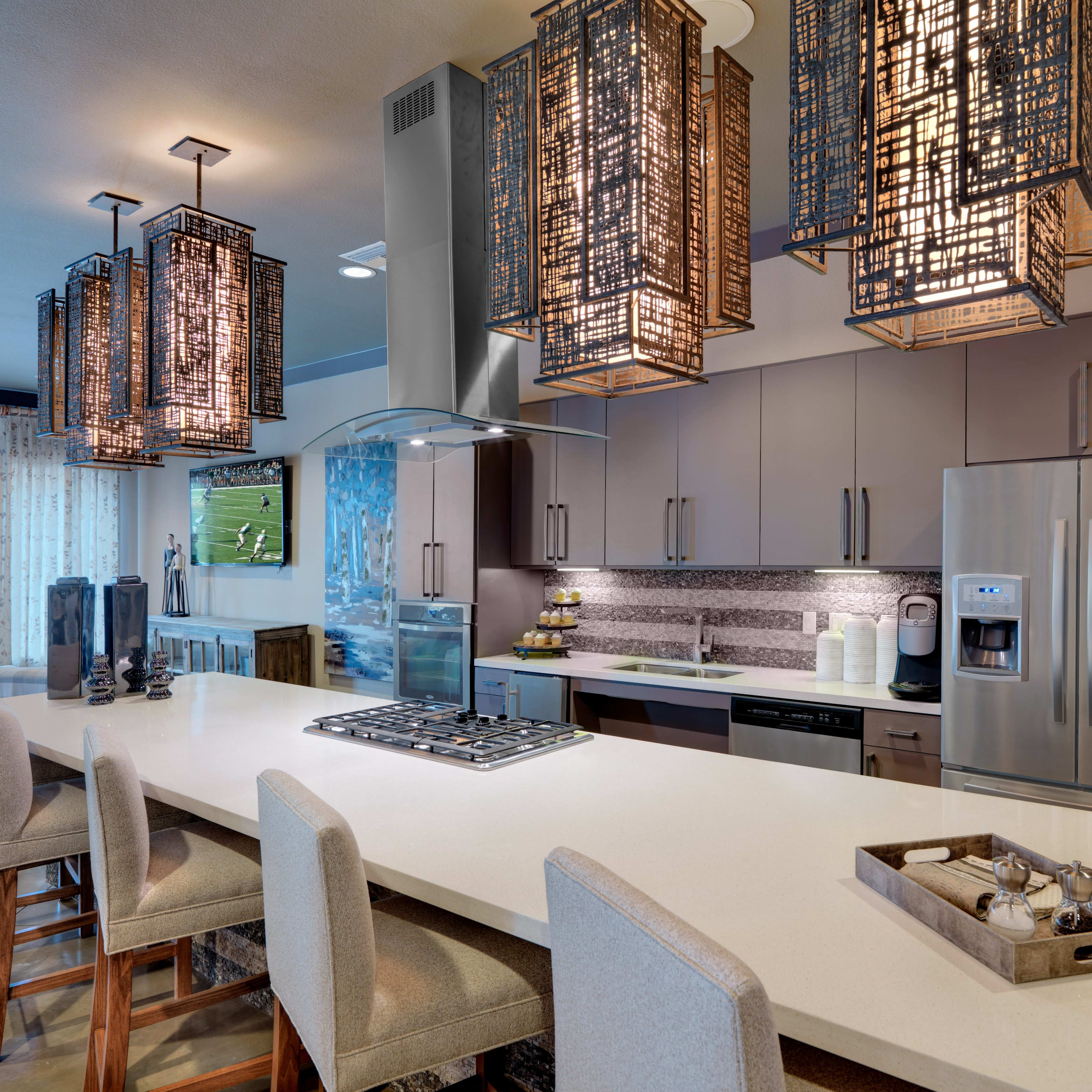 A modern kitchen with a large island, featuring pendant lights and contemporary appliances.