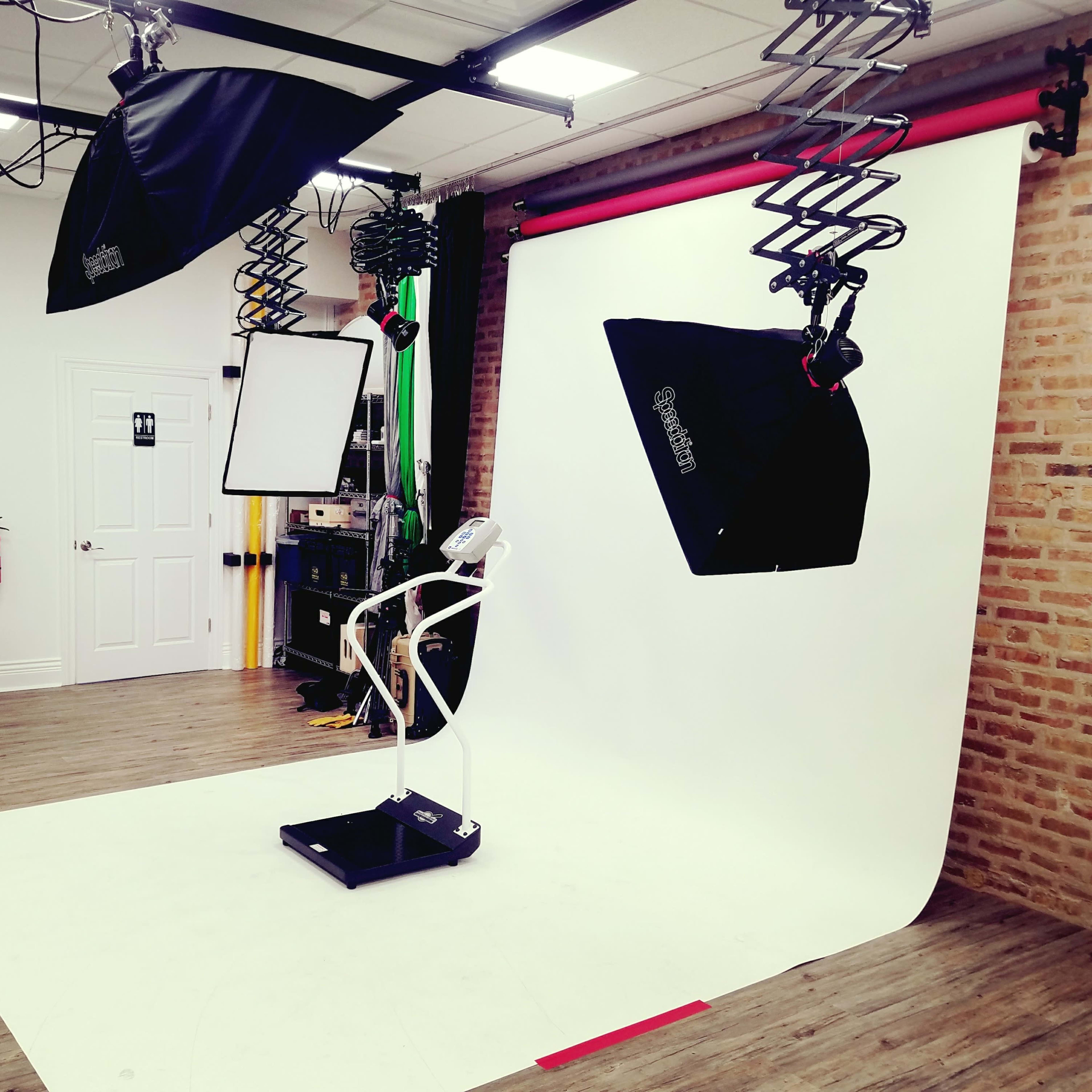 A photography studio equipped with lighting equipment, a backdrop, and a positioning platform for subjects.