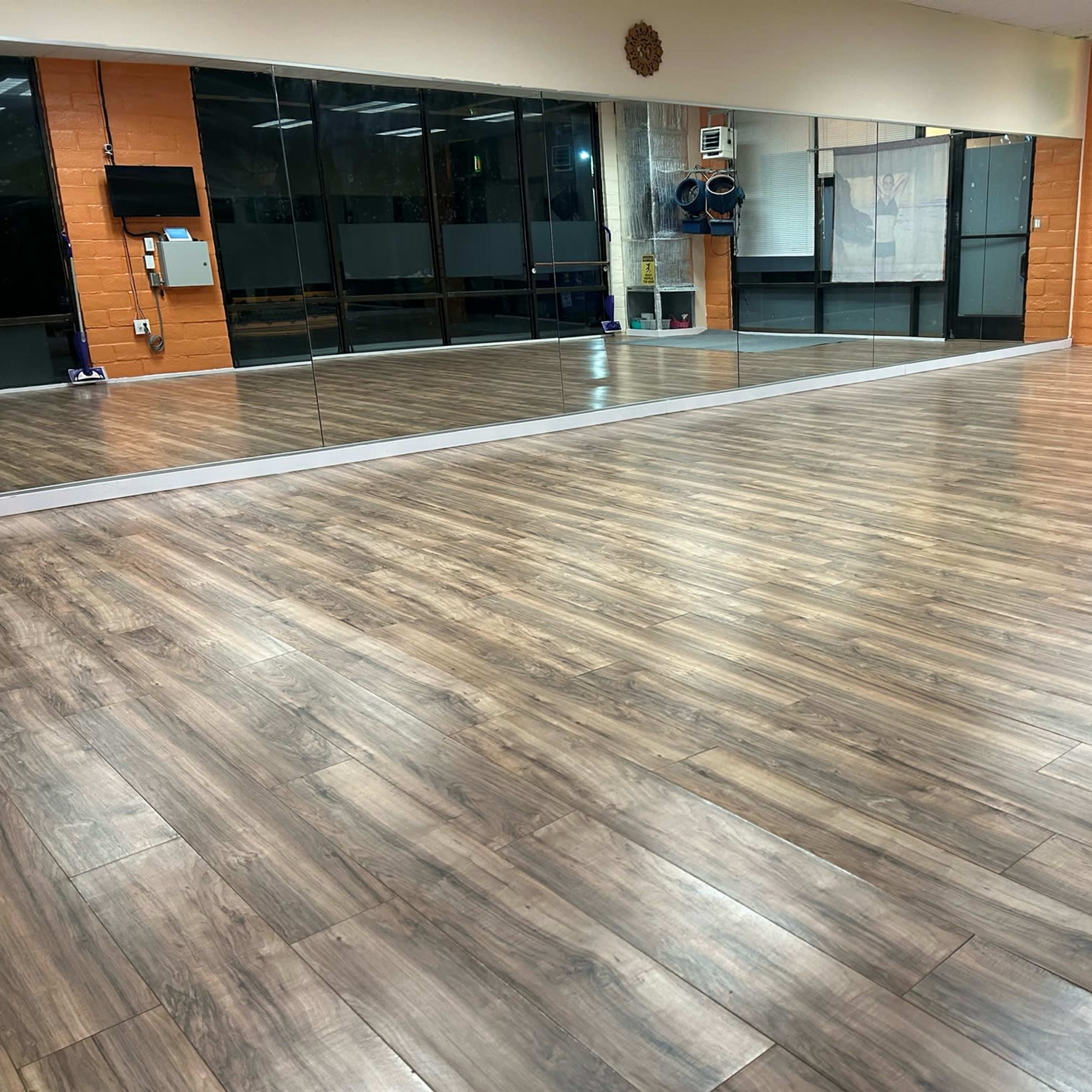 A spacious studio with a wooden floor and large mirrors reflecting the interior.