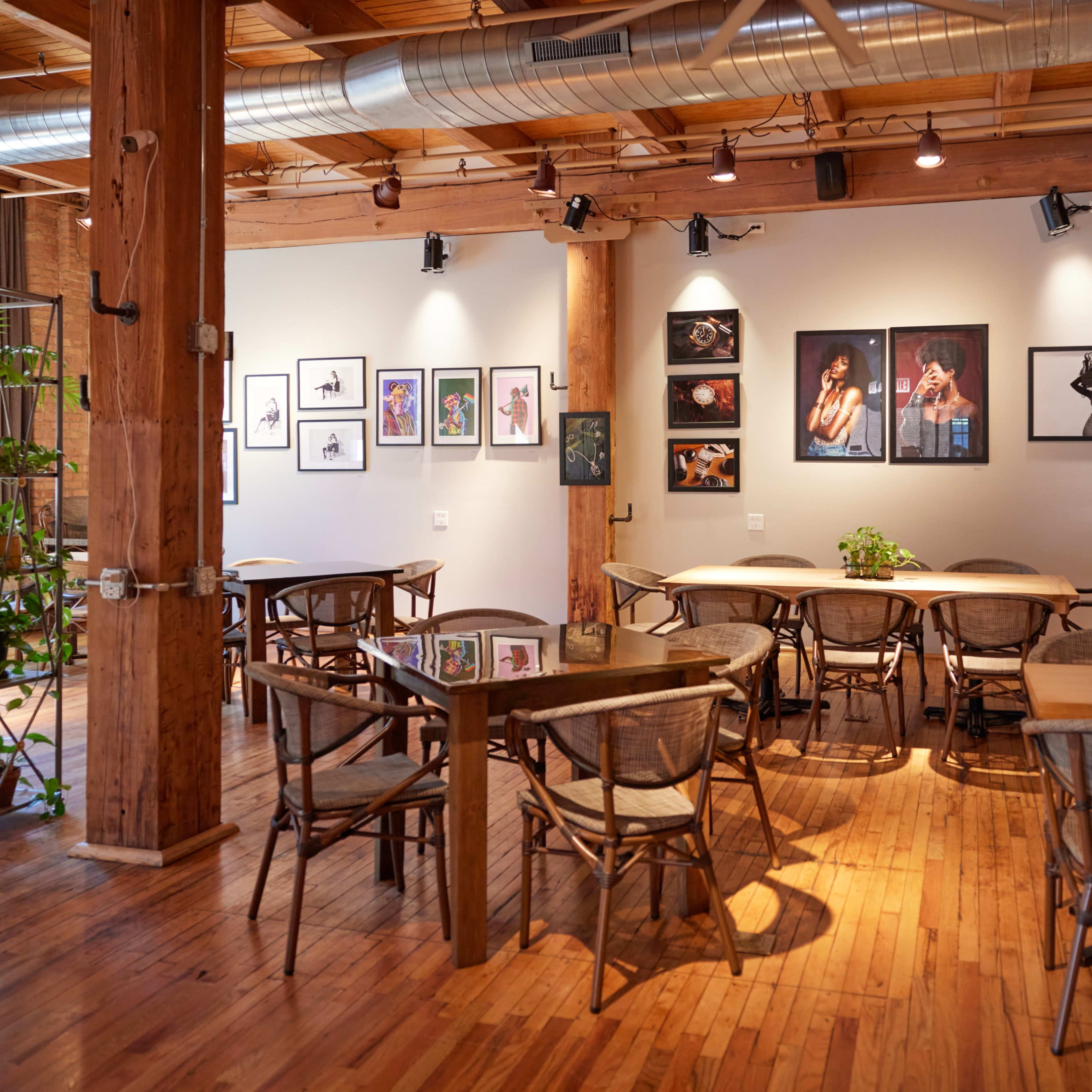An interior of a restaurant with wooden floors and walls, featuring several framed artworks on the walls and tables set for dining.