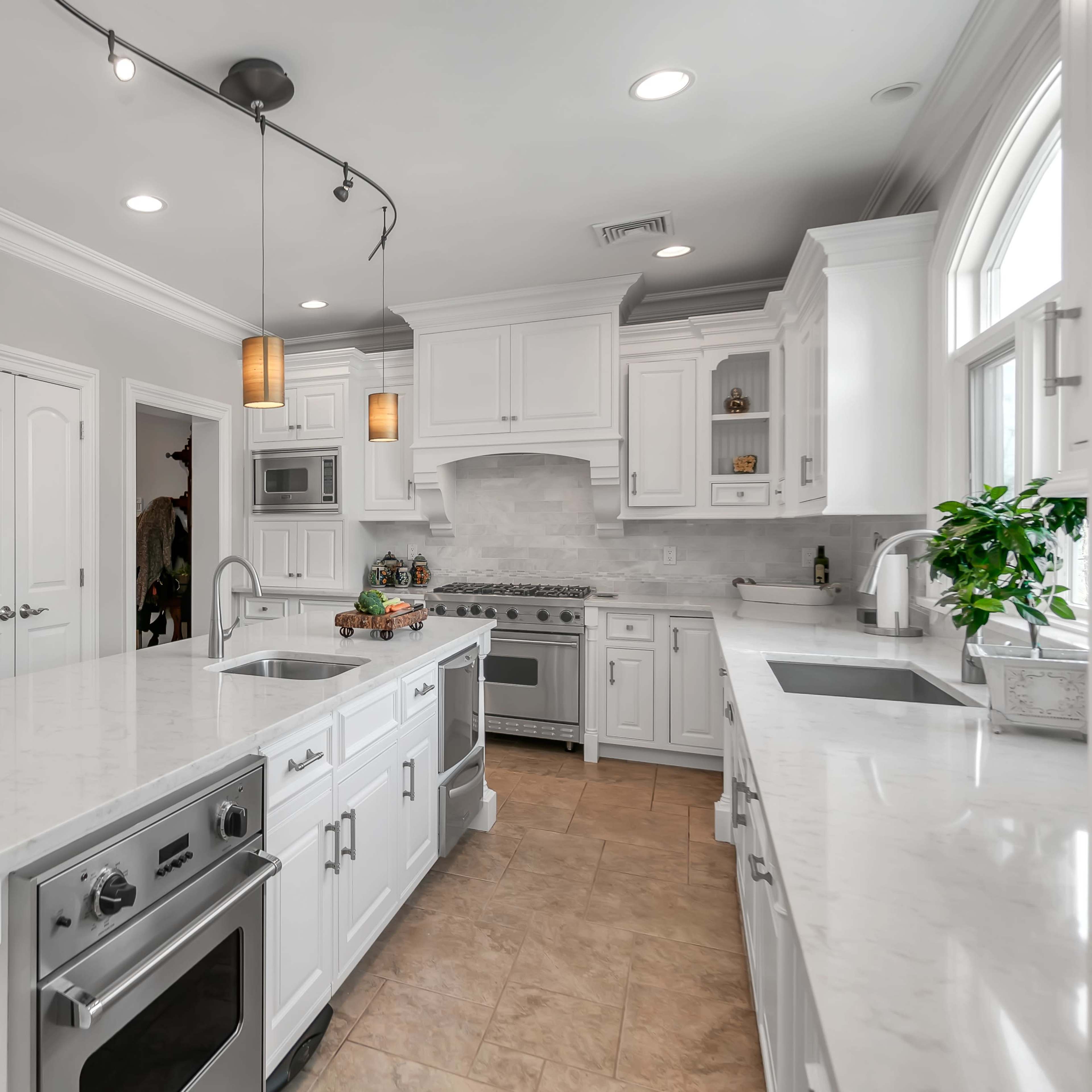 A modern kitchen featuring white cabinets, a central island with a sink, and pendant lighting.