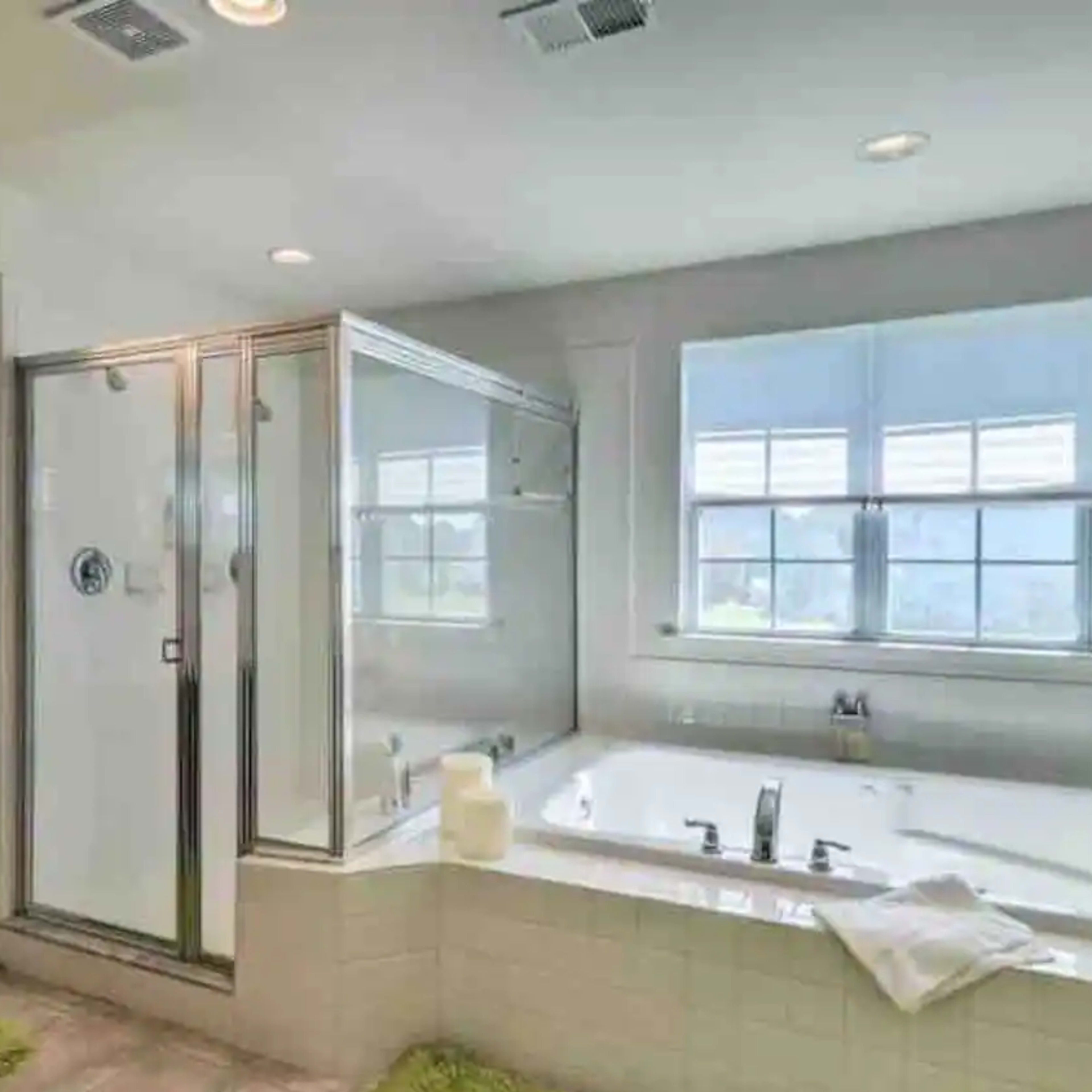 A bathroom featuring a glass shower enclosure, a large bathtub, and a vanity with a sink and mirror.