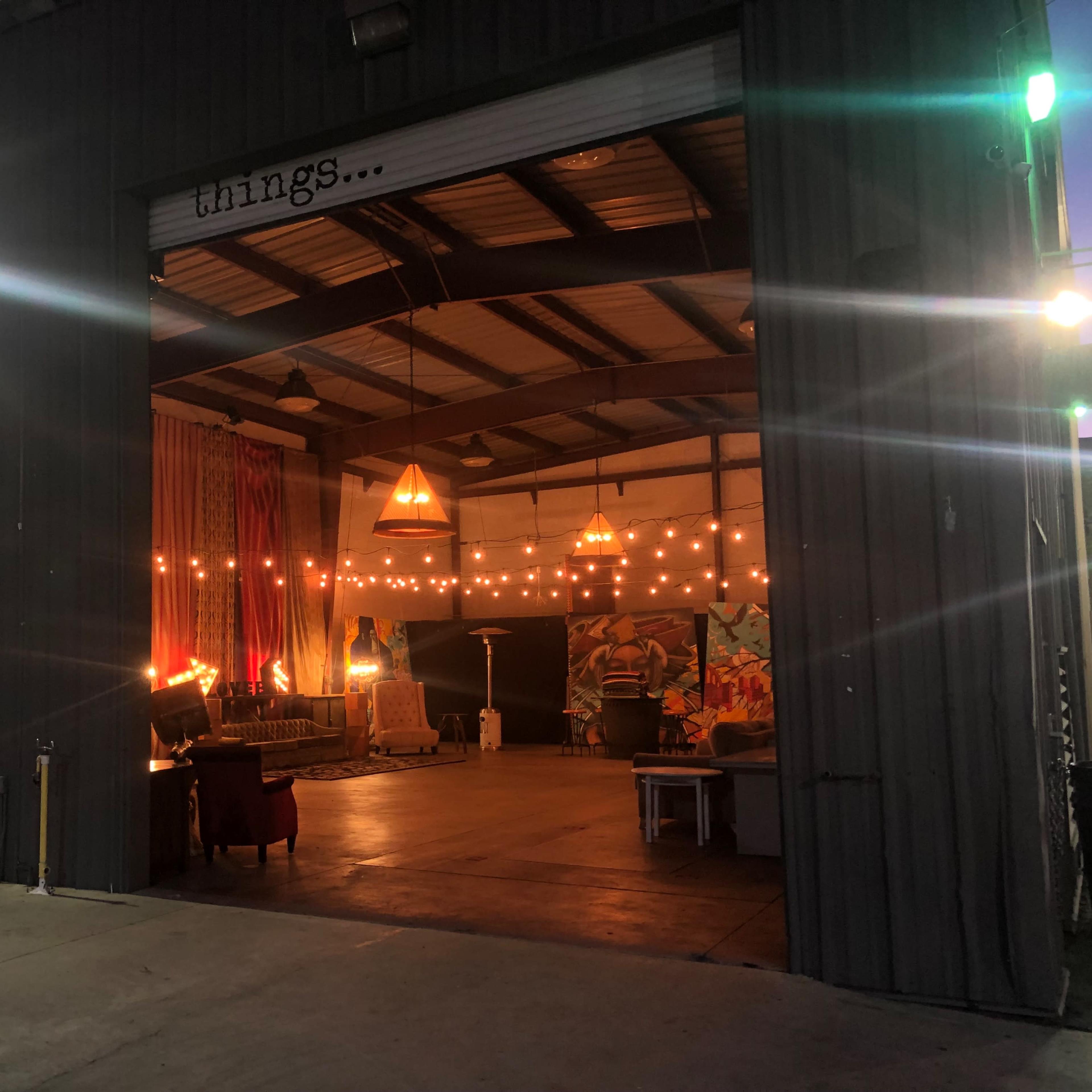 A large garage-style space features an open interior with decorative lighting and artwork, alongside a silhouette mural on the exterior wall.