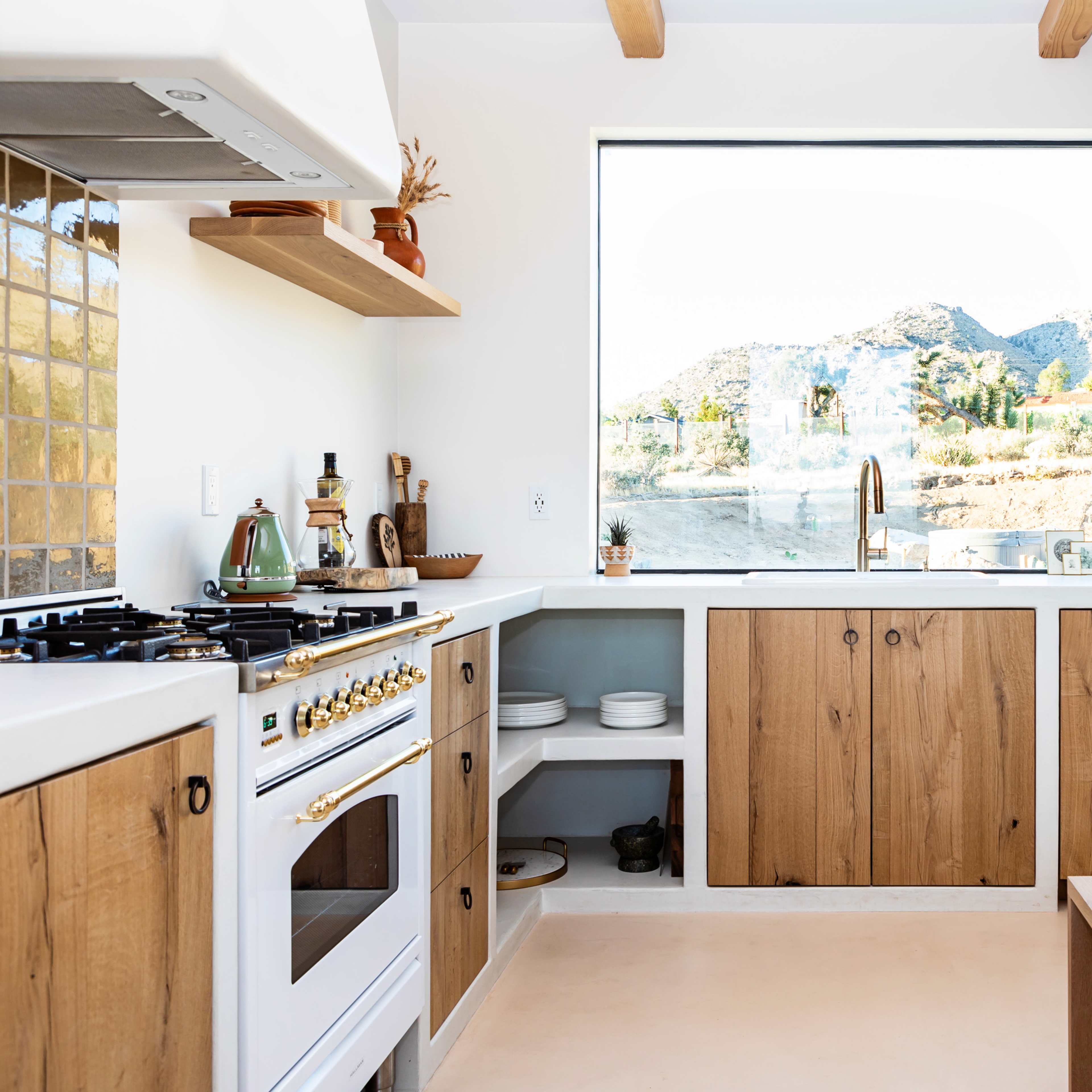 A modern kitchen with wooden cabinets and a large window overlooking a mountainous landscape.