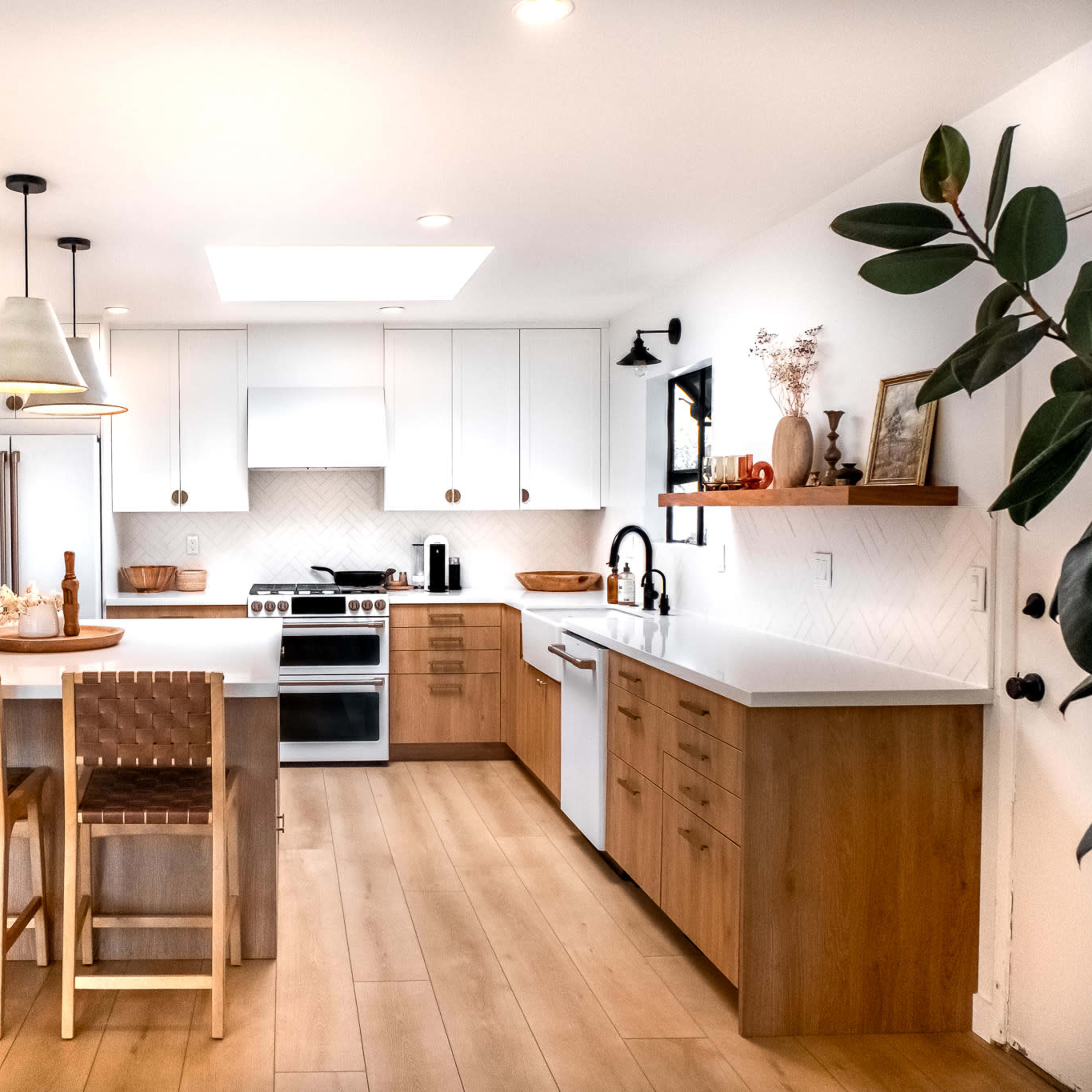 A modern kitchen features white cabinets, a central island with seating, and stainless steel appliances, with a dining area visible in the background.