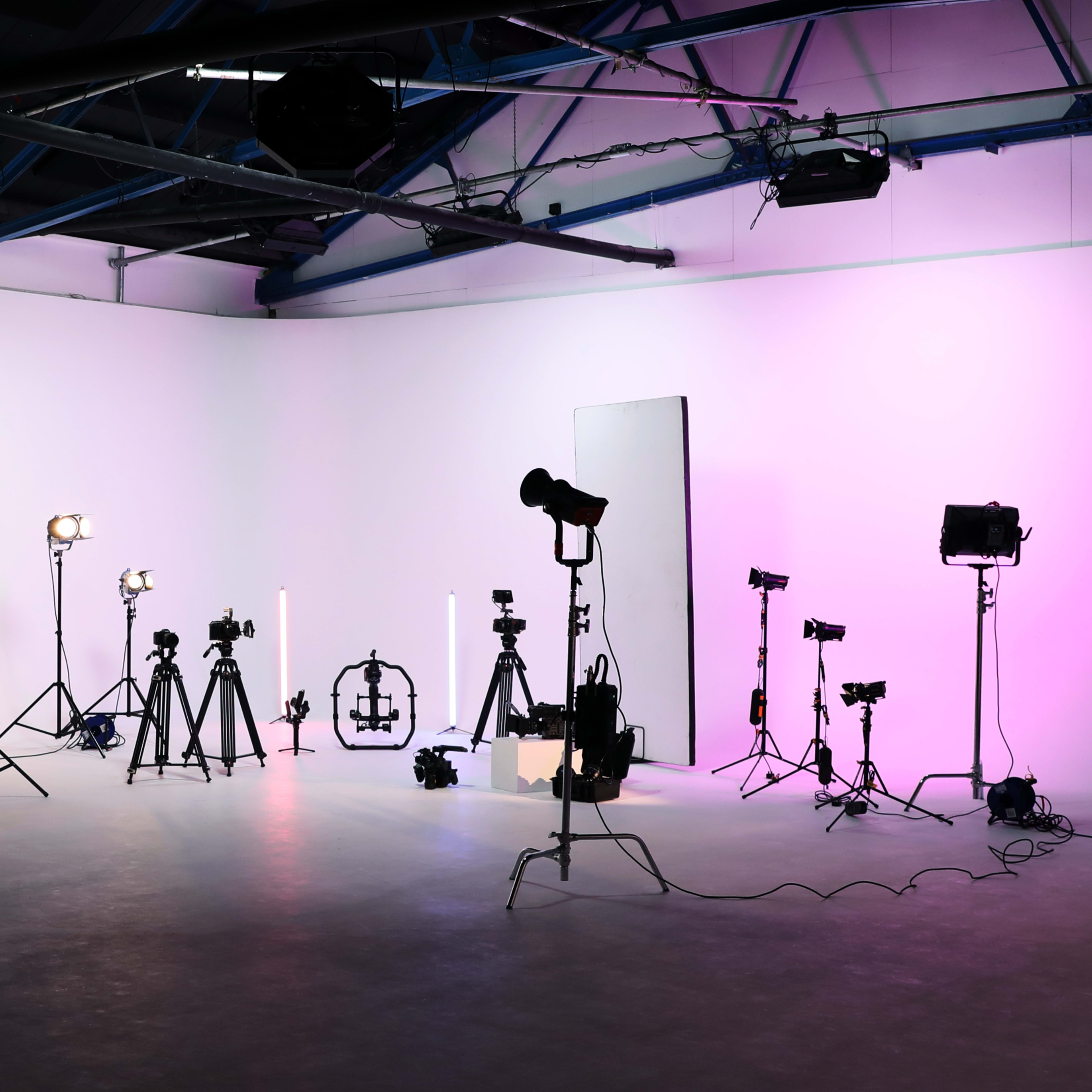 A photography studio equipped with various lighting setups and tripods arranged on a smooth surface.