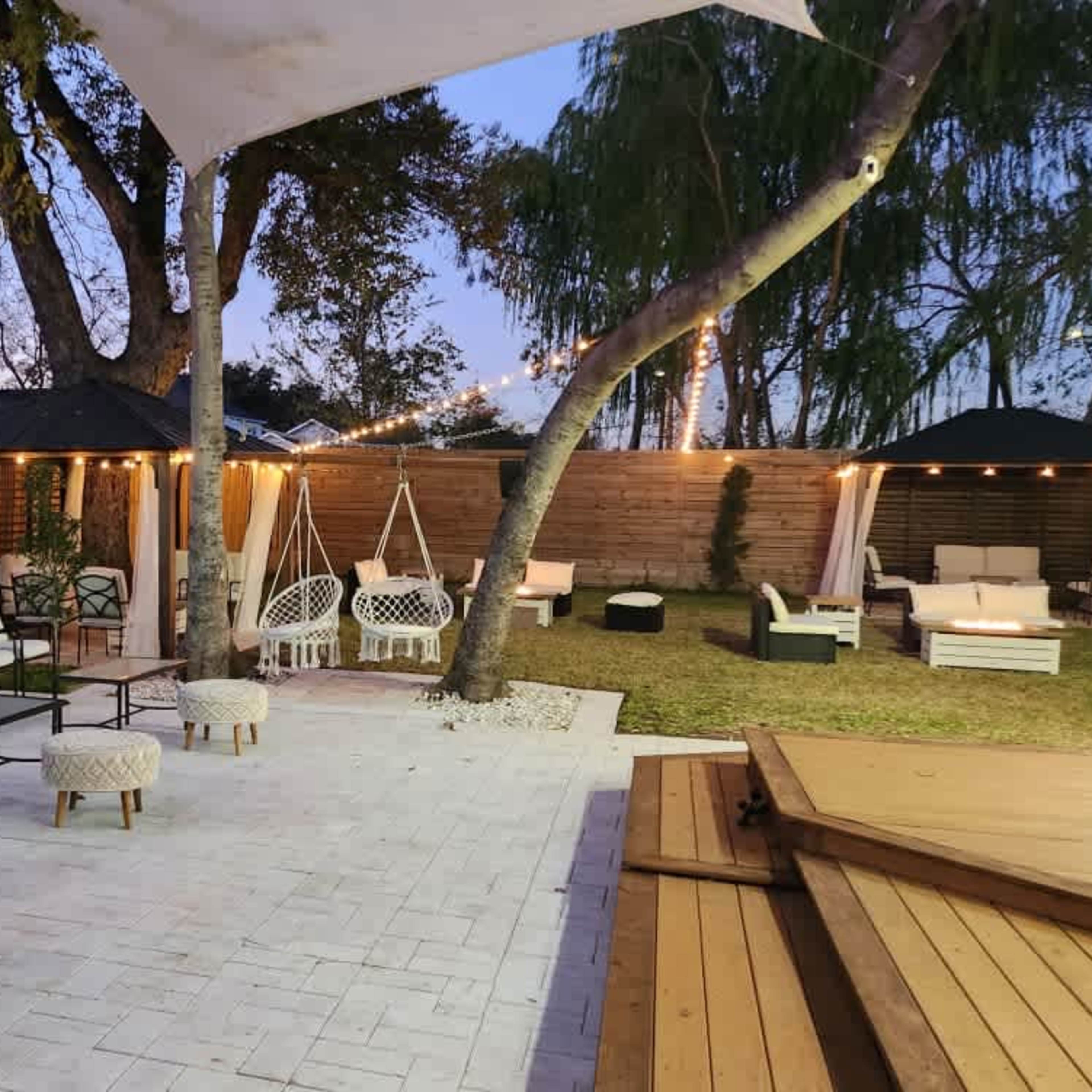 A landscaped outdoor space with seating areas, a pergola, and decorative lighting.
