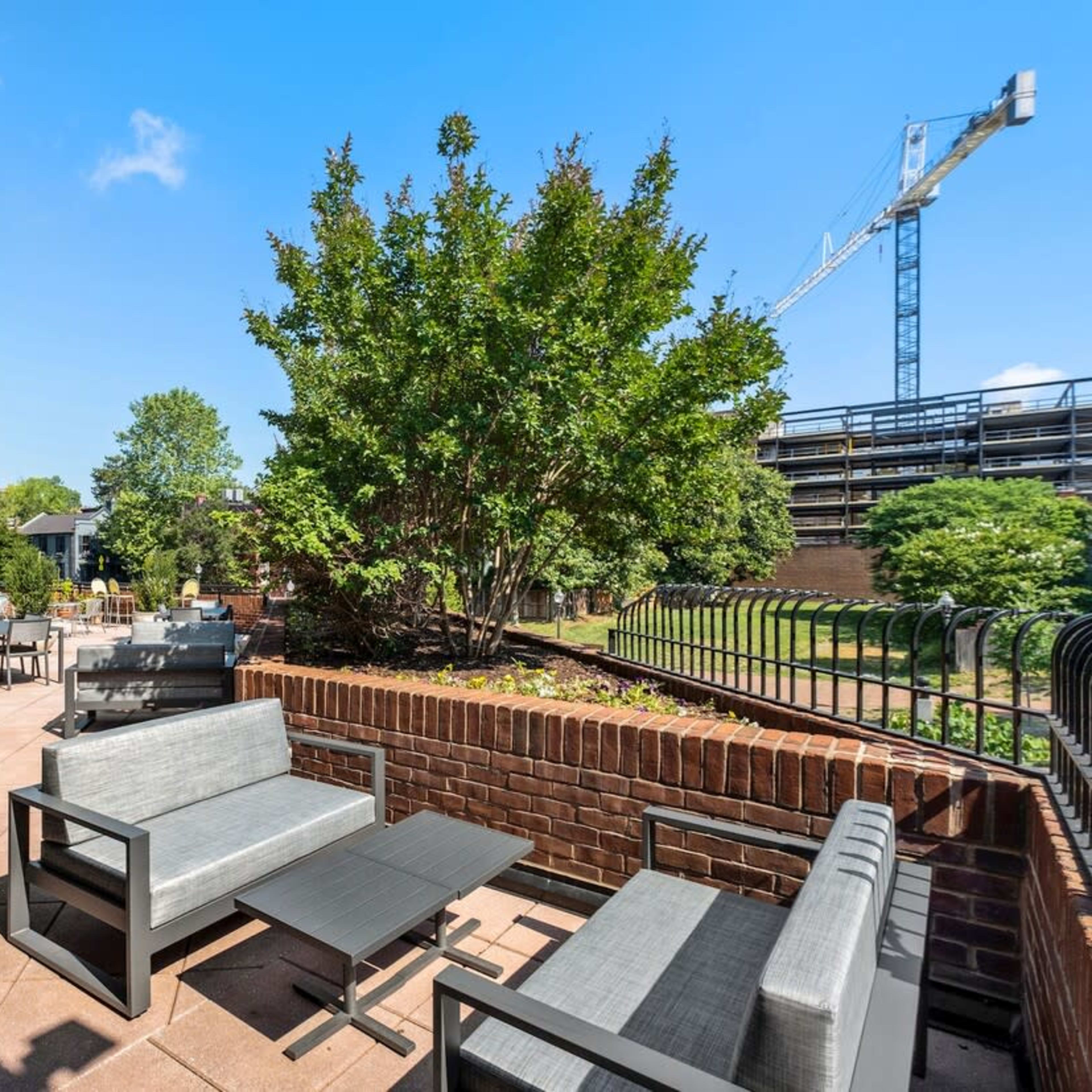 A patio area with modern furniture overlooks greenery and a construction site in the background.
