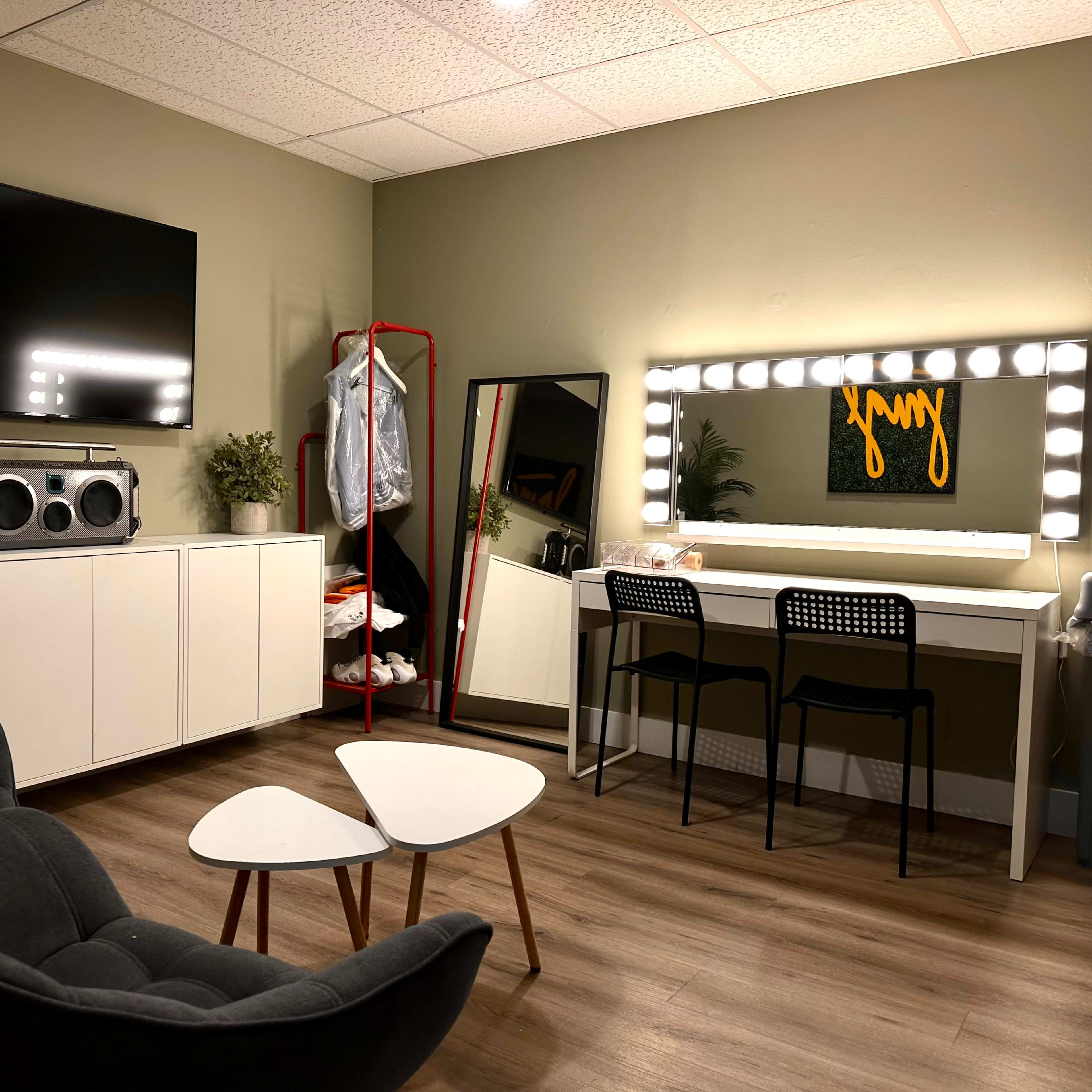 A modern room with a large mirror and vanity lights, a sofa, a small coffee table, and a television mounted on the wall.