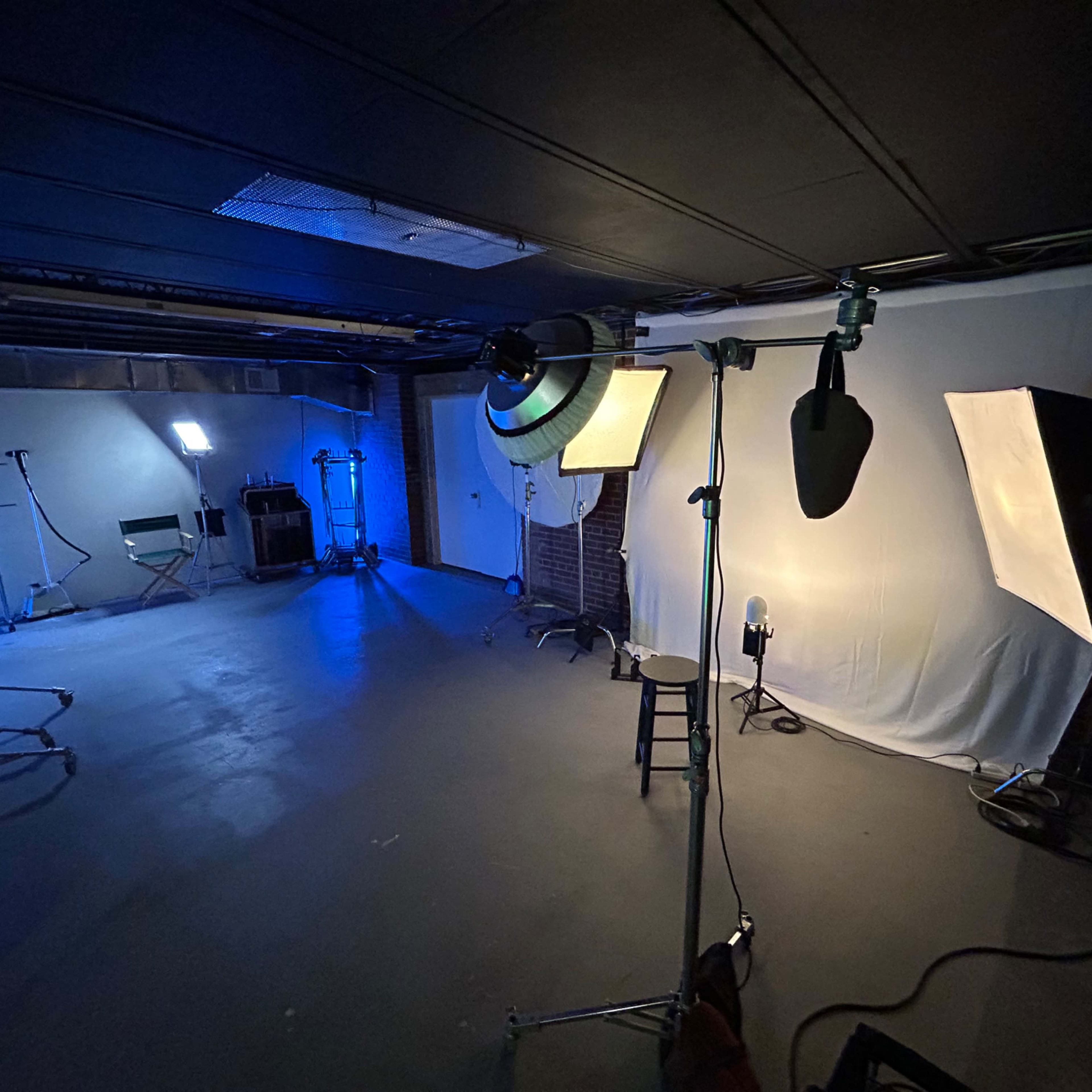 A photography studio with various lighting equipment, a stool, and a backdrop.