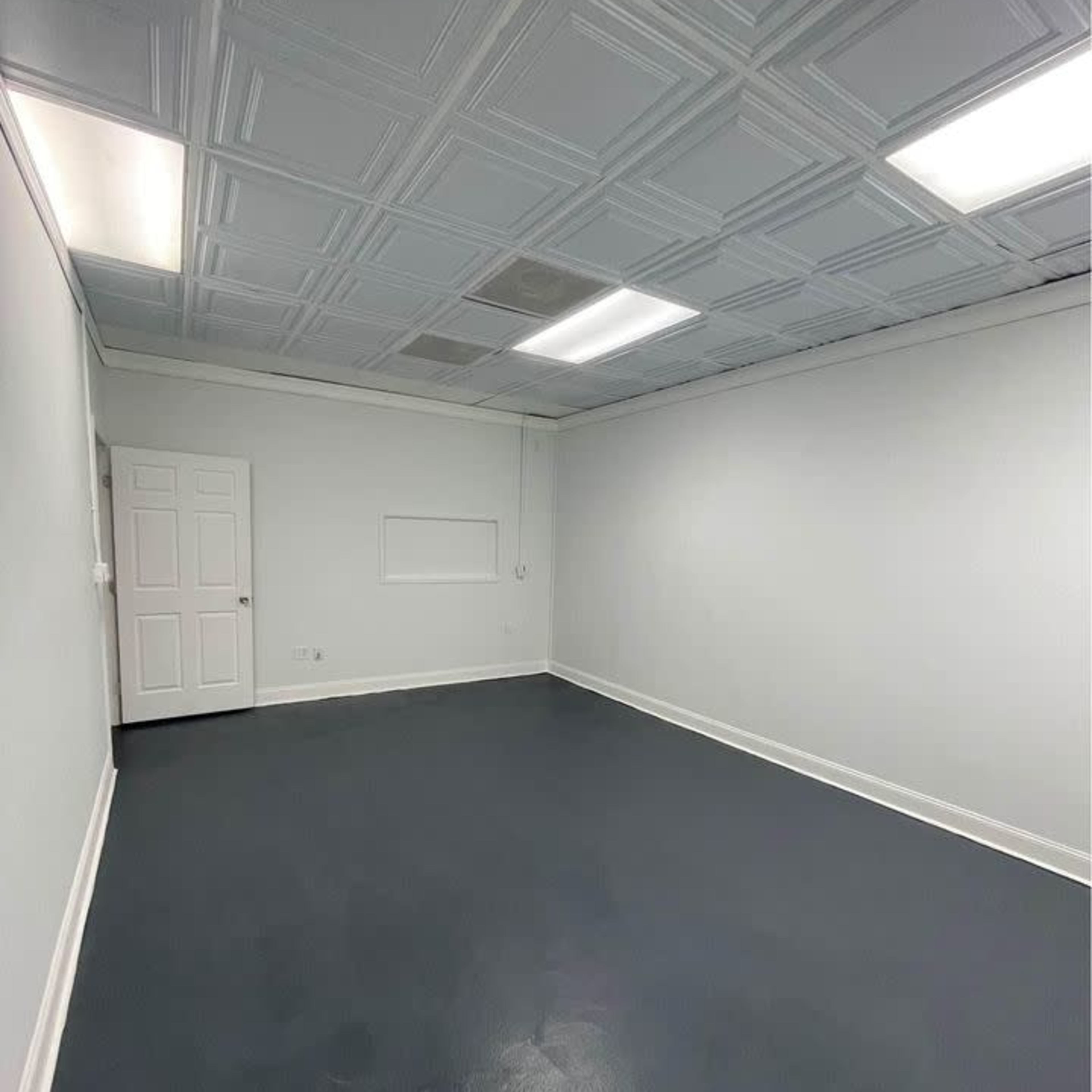 An empty room with gray walls, a dark floor, and a ceiling featuring a patterned design.