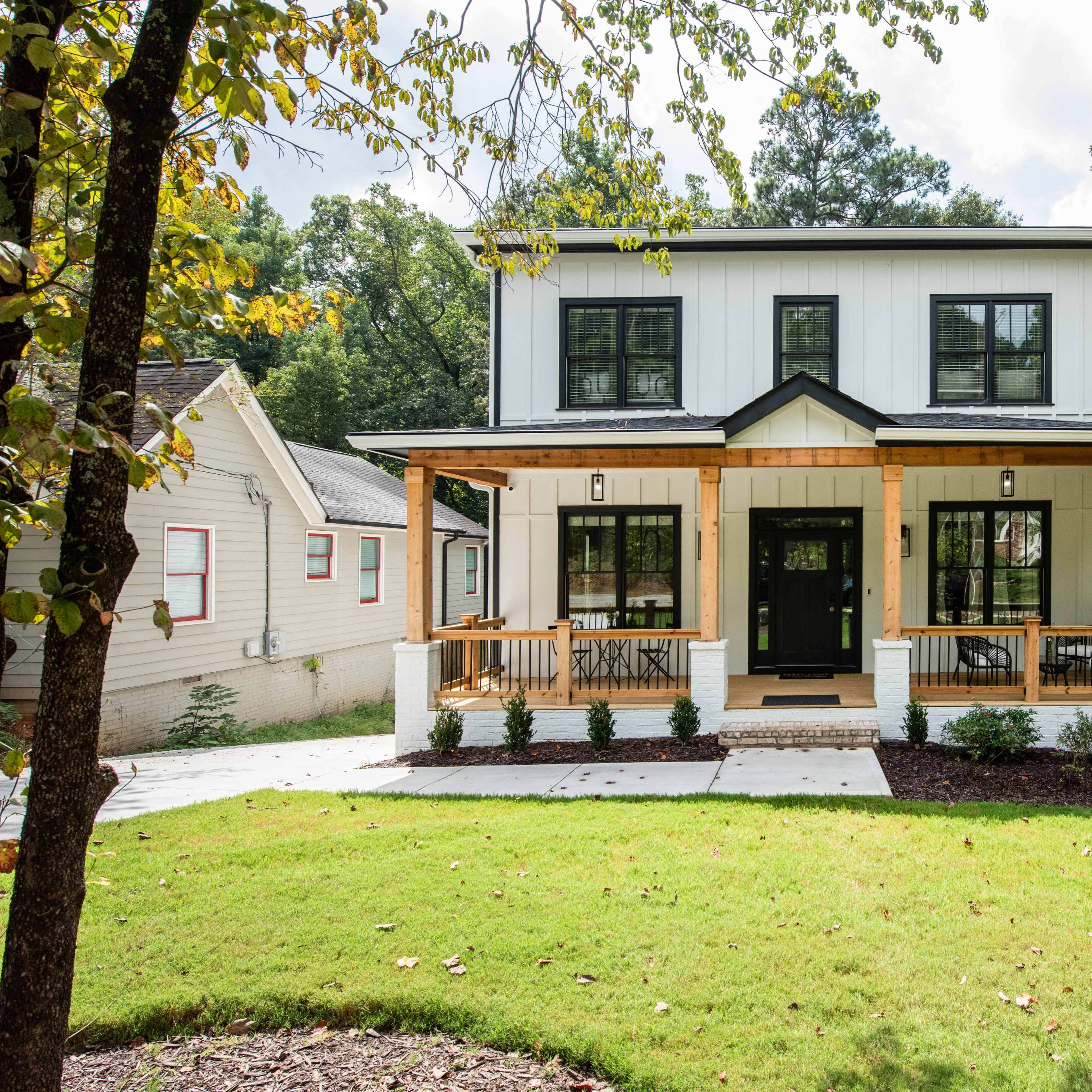 A two-story house with a front porch, white and black exterior, and landscaped yard is visible in the scene.