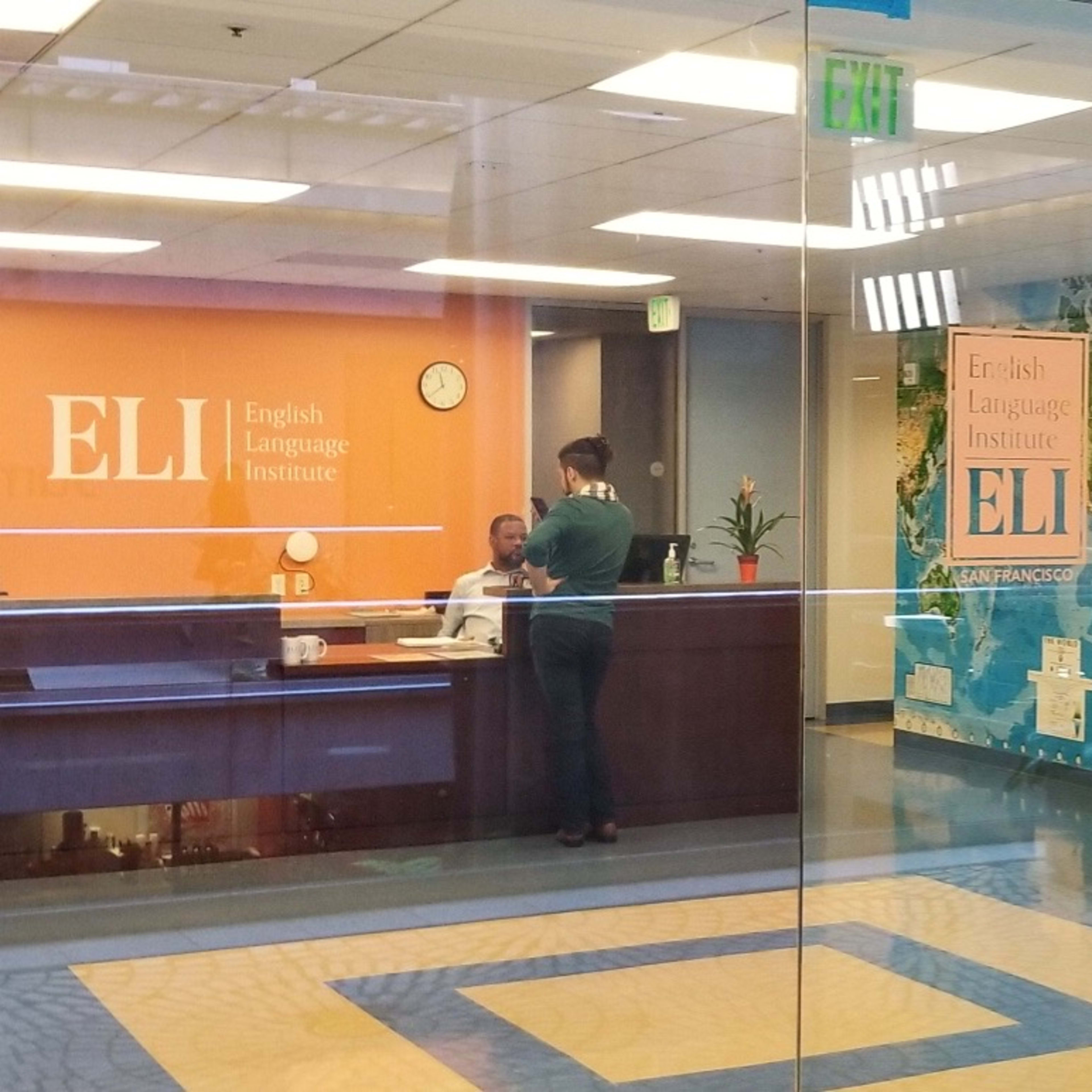 The reception area of the English Language Institute, featuring a front desk, a map mural, and multilingual welcome messages on the walls.