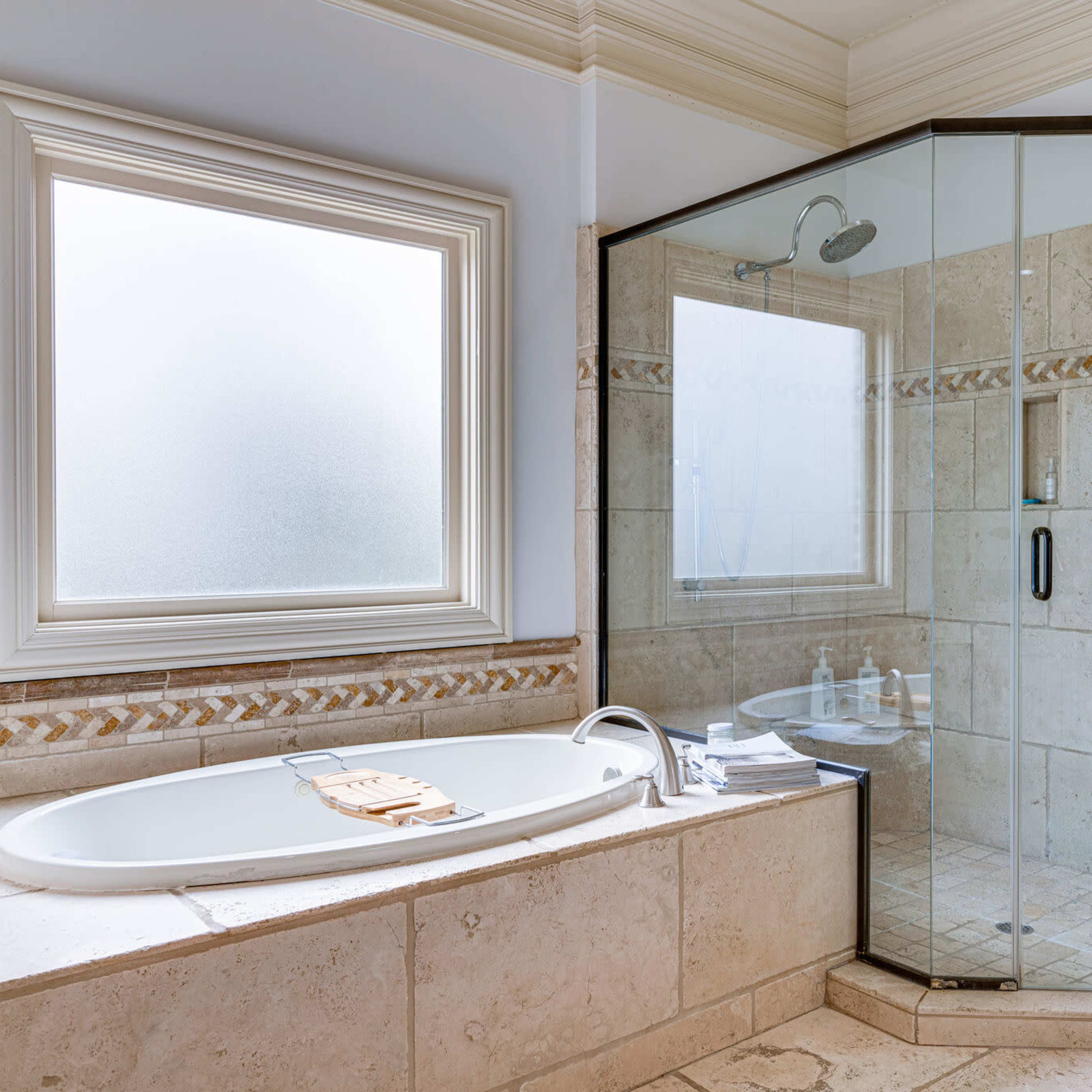 A bathroom featuring a glass-enclosed shower and a bathtub near a window.