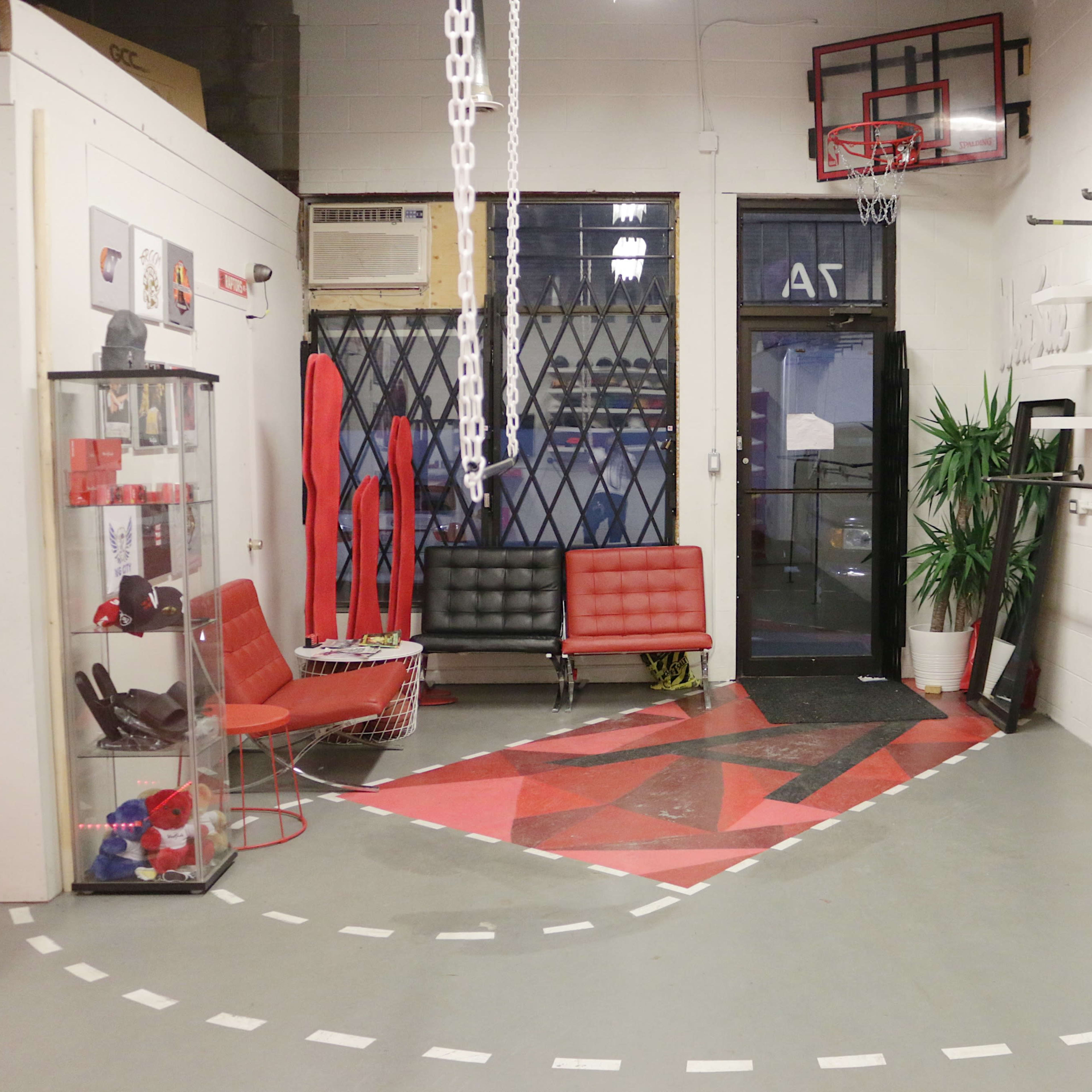 A modern, minimalist room featuring red and white decor, seating areas, exercise equipment, and a basketball hoop.
