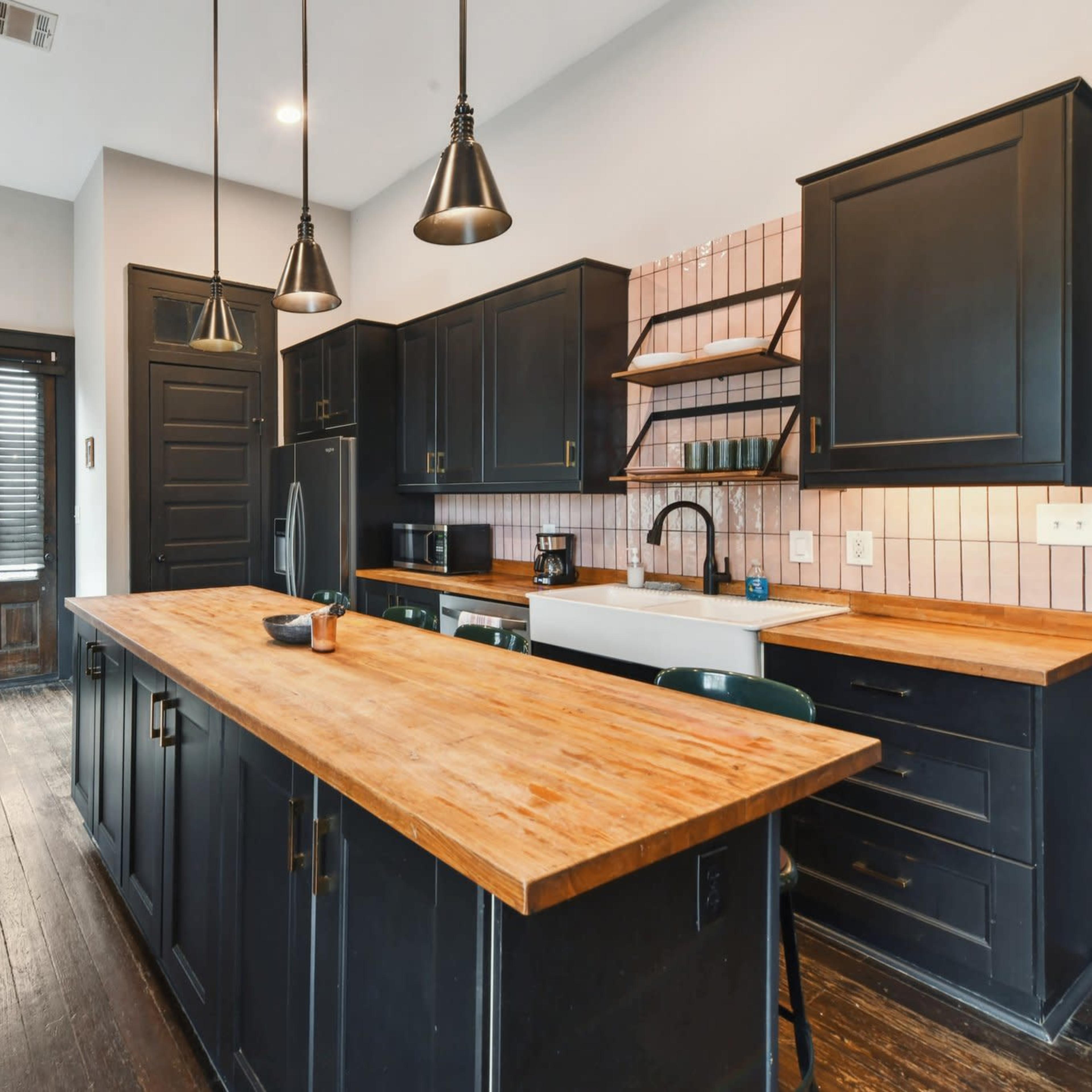 The kitchen features dark cabinetry with wooden countertops, a large sink, and brick accents on the wall.
