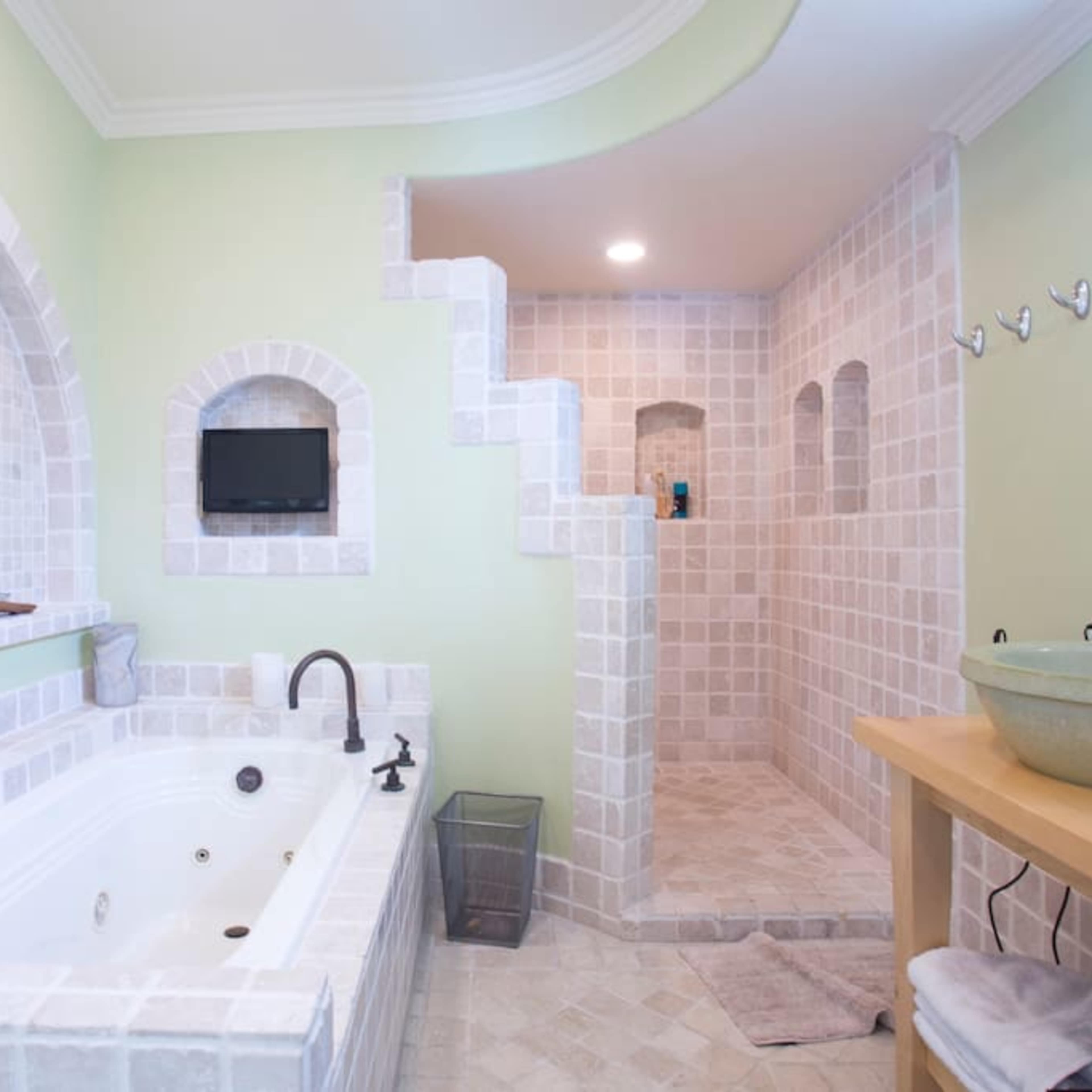 A spacious bathroom featuring a large jacuzzi tub, a walk-in shower, and stone-tiled walls.