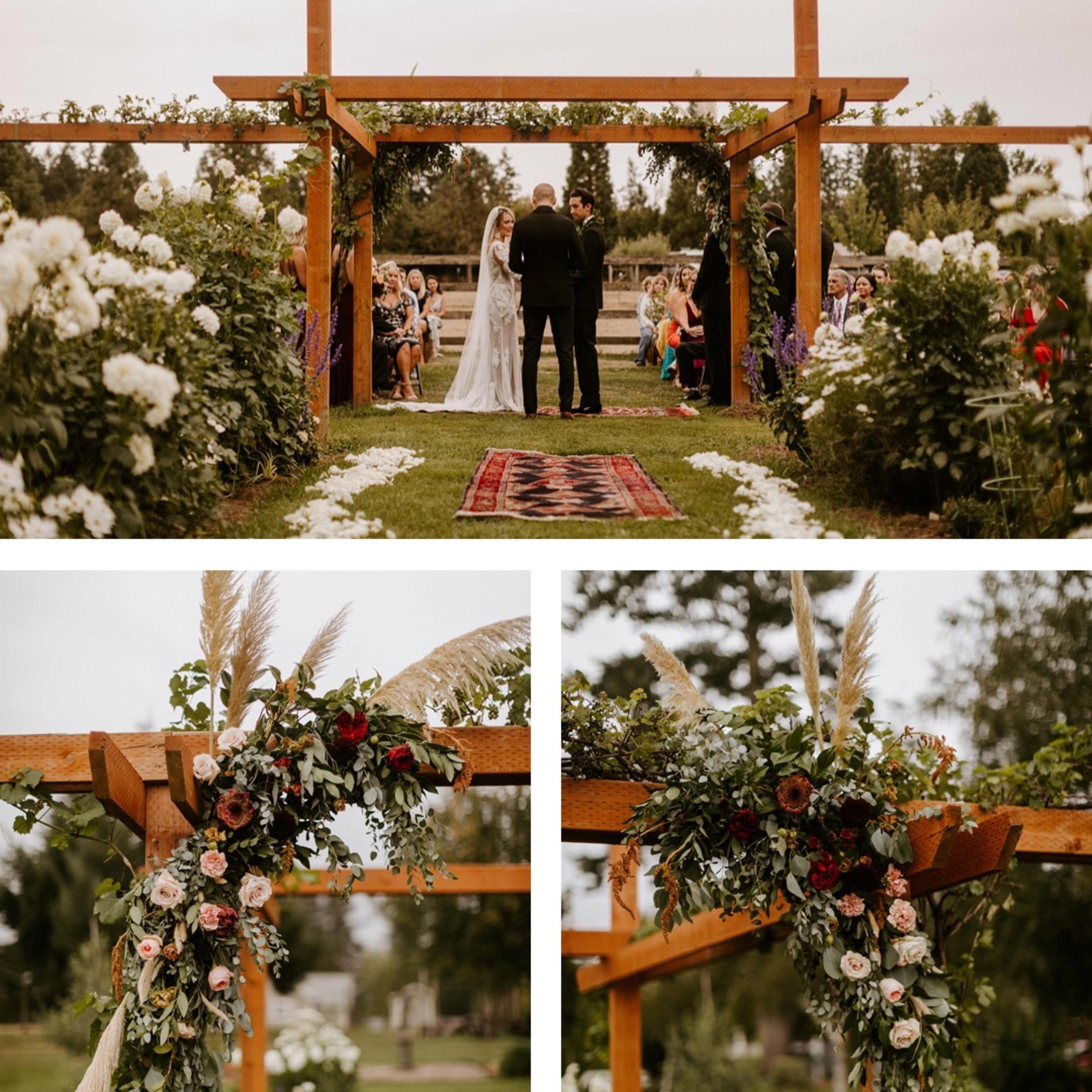 A wedding ceremony takes place under a decorated wooden arbor surrounded by greenery and floral arrangements.