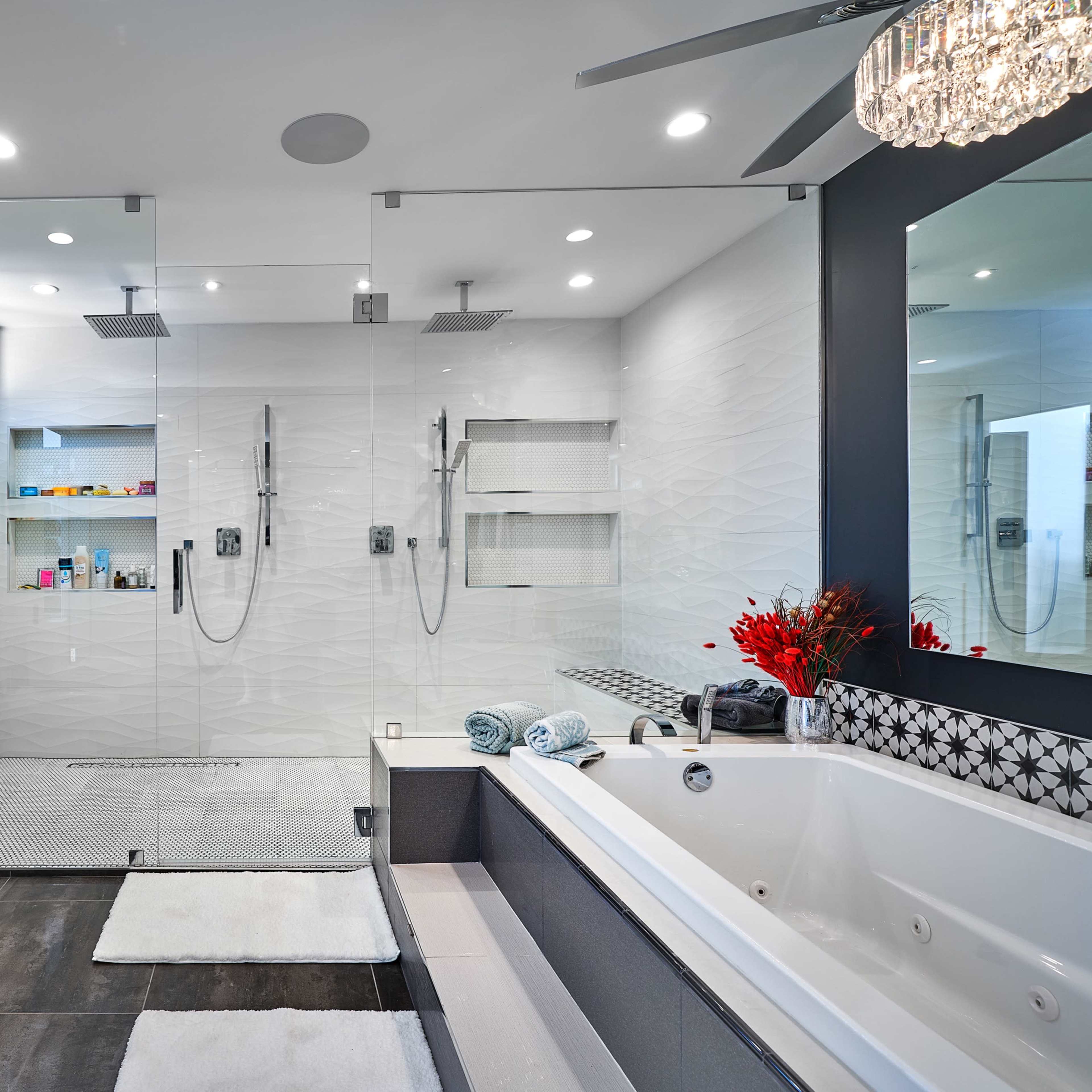 A modern bathroom featuring a glass shower, a large soaking tub, and a flat-screen TV mounted on the wall.