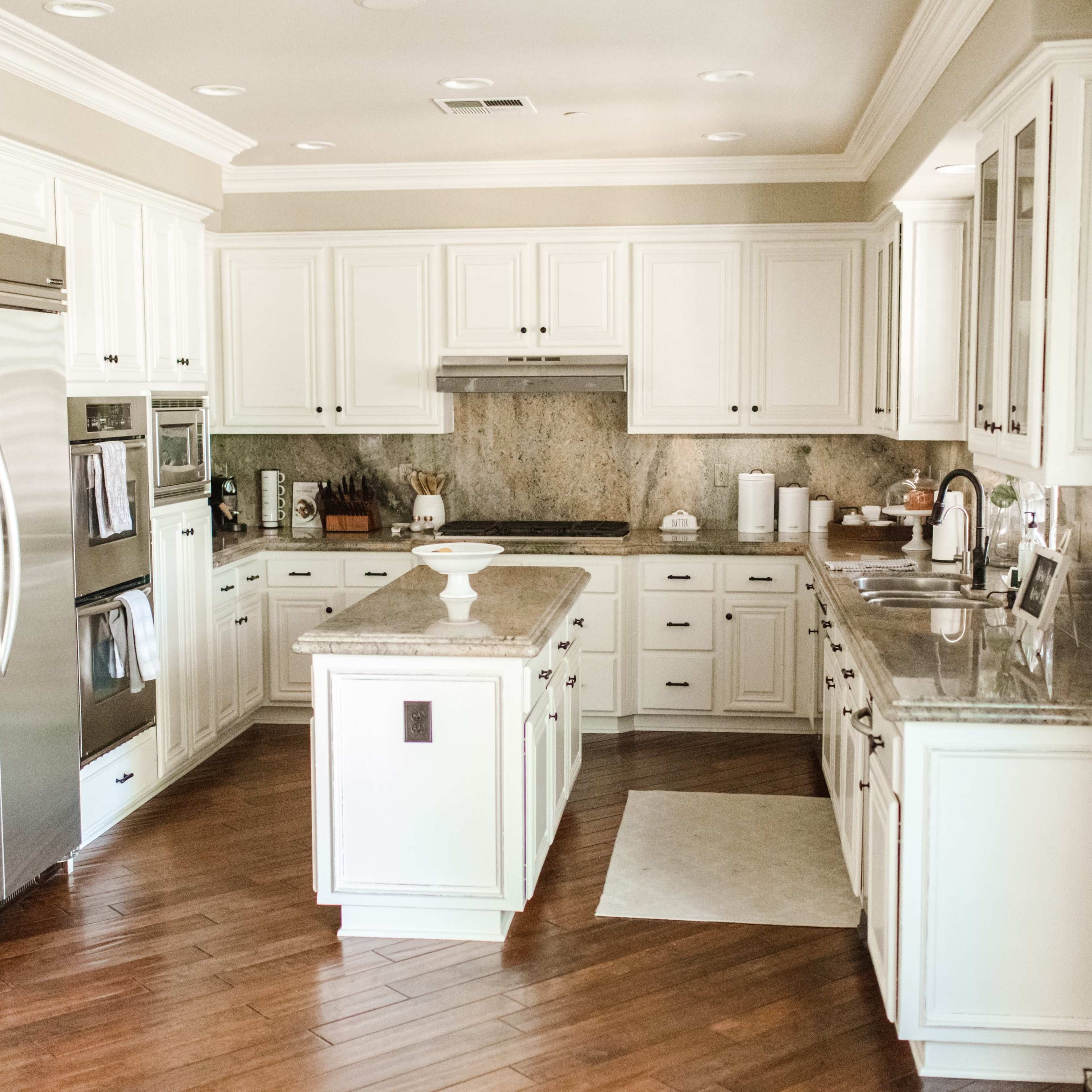 A modern kitchen with white cabinetry, stainless steel appliances, and a central island.