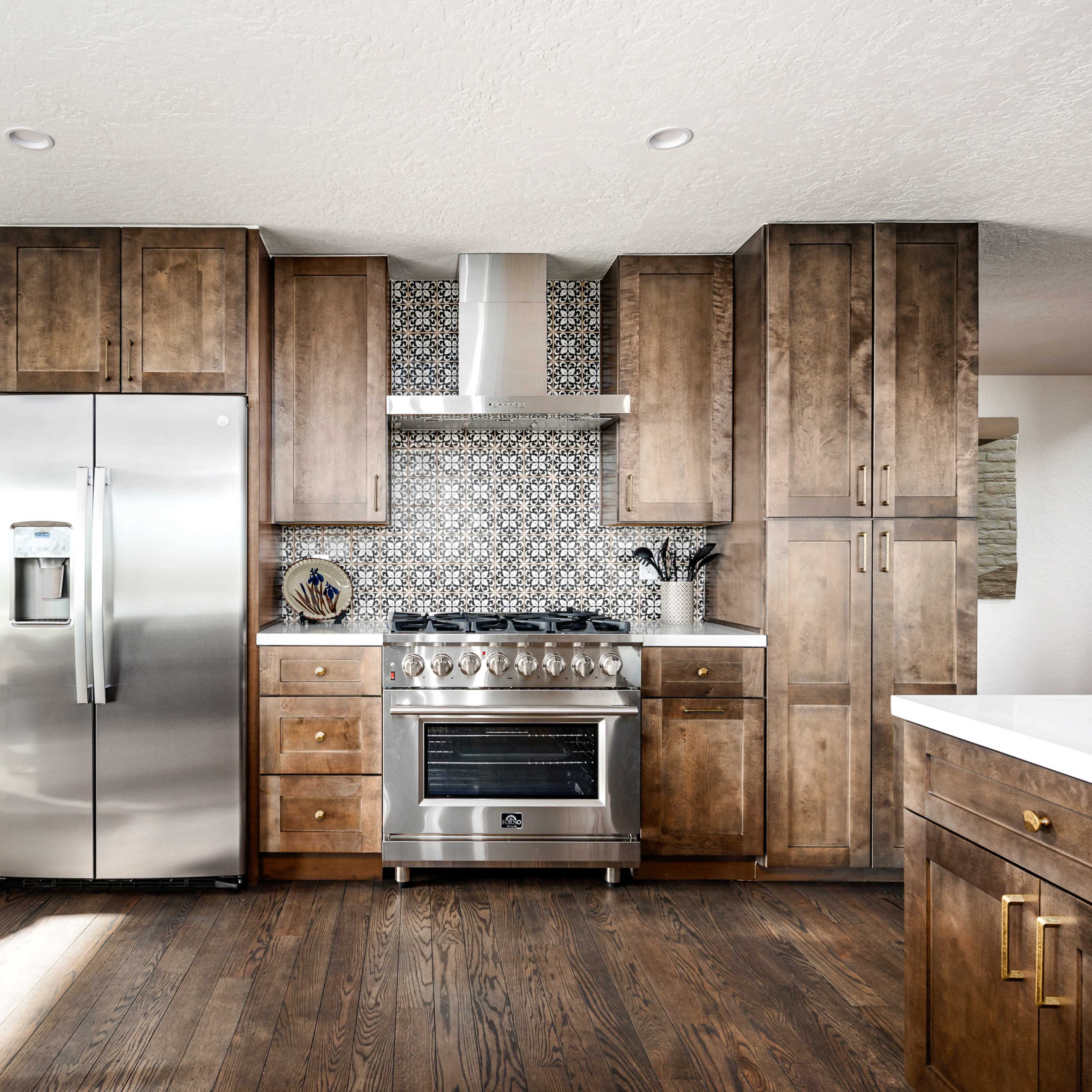 A modern kitchen featuring wooden cabinetry, stainless steel appliances, and a patterned tile backsplash.