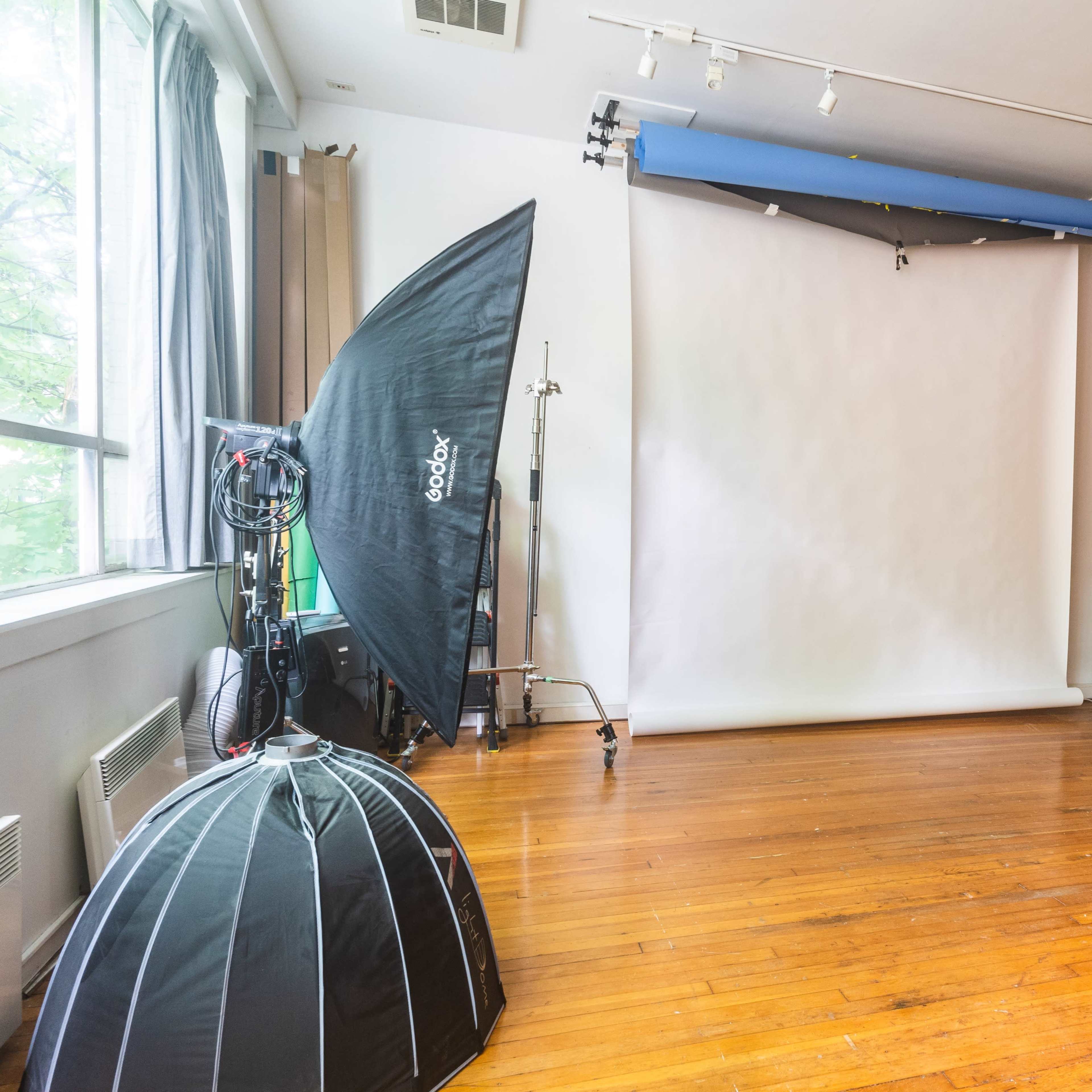 A photography studio with a large softbox, a blank backdrop, and wooden flooring.