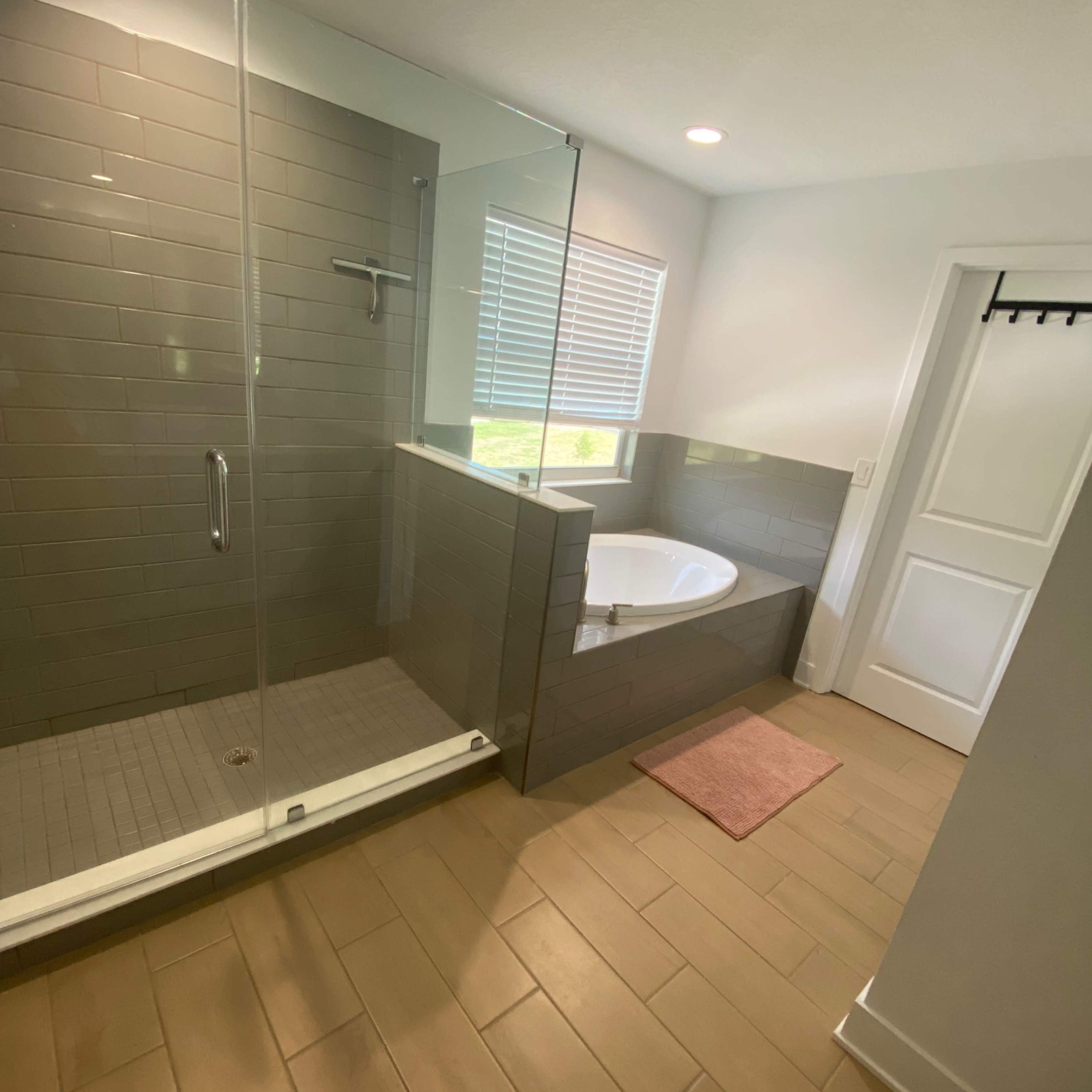 A modern bathroom featuring a glass-enclosed shower, a freestanding bathtub, and a window with natural light.