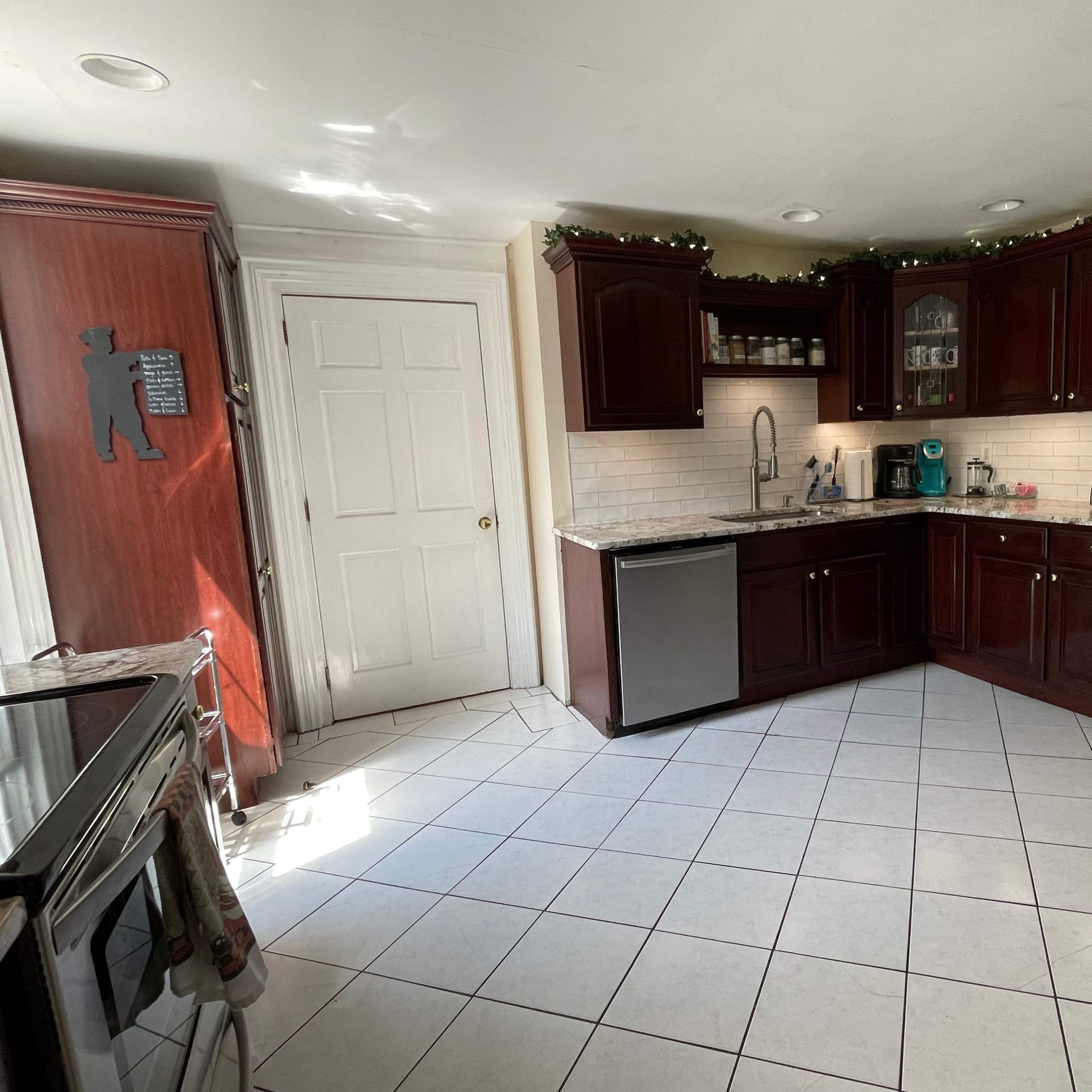 A kitchen with dark wooden cabinets, tile flooring, and stainless steel appliances.