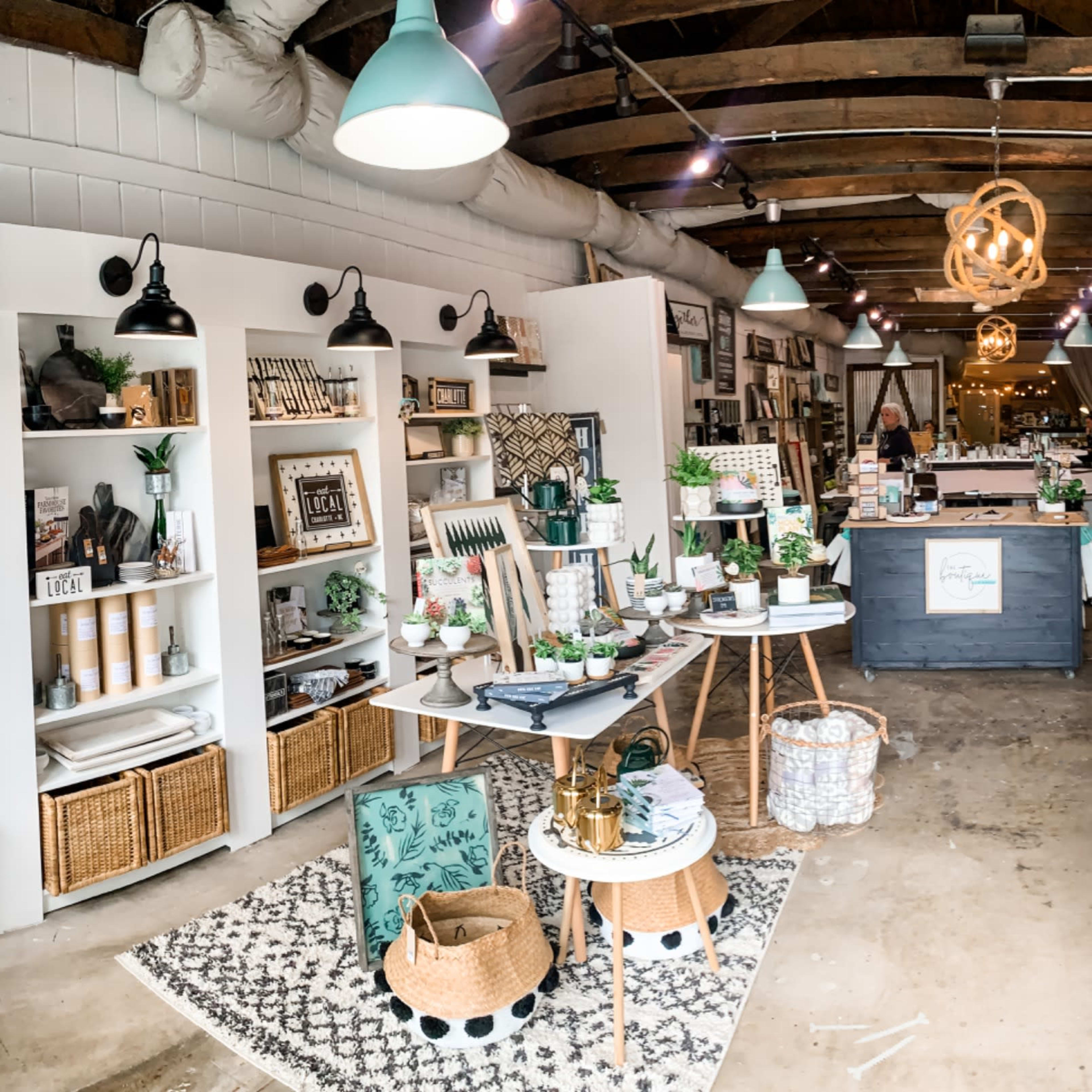 A well-organized interior of a retail store featuring various home decor items, plants, and furniture arranged on display shelves and tables.