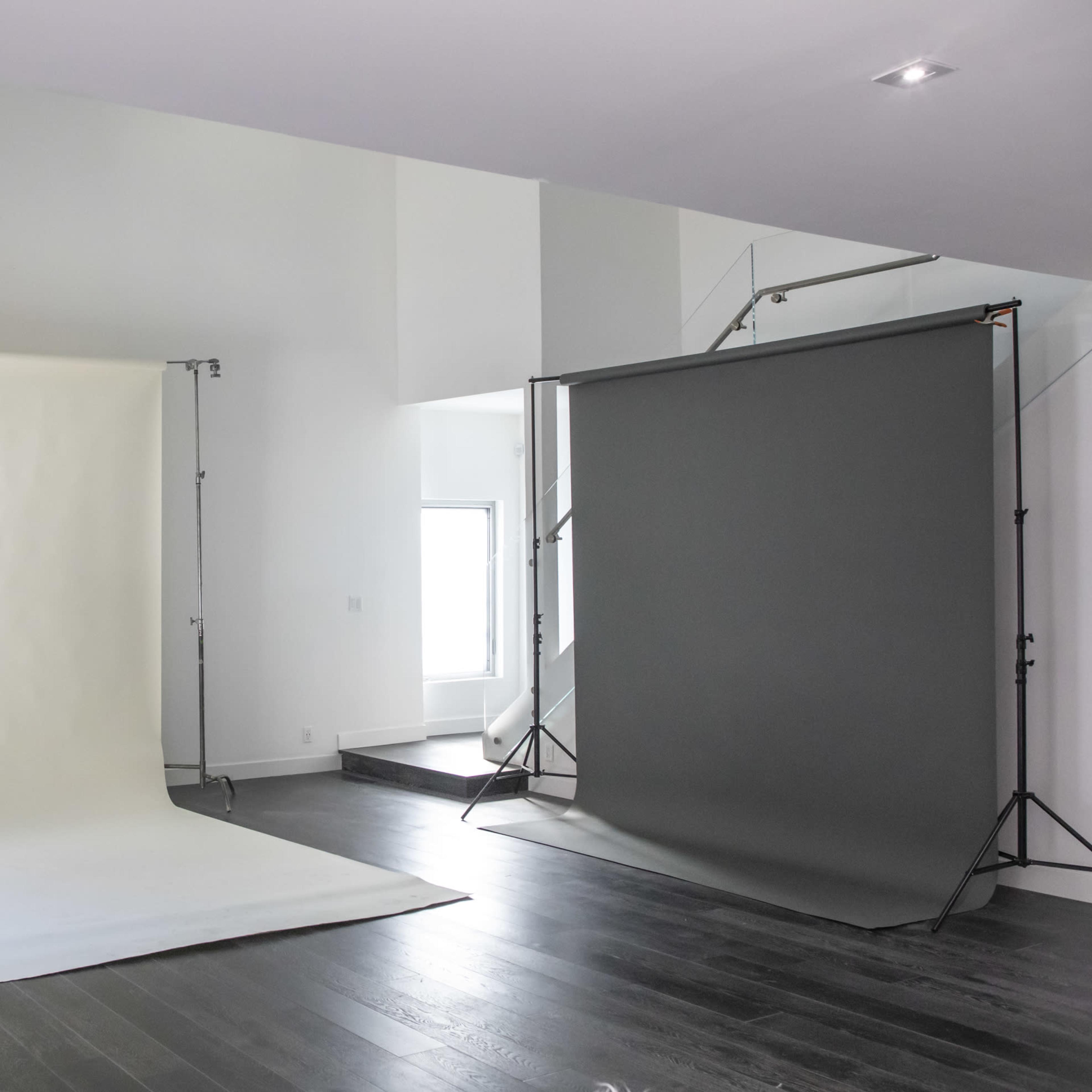 A spacious, empty room with hardwood flooring and a large wall featuring red text advertising reduced rates for various production services.