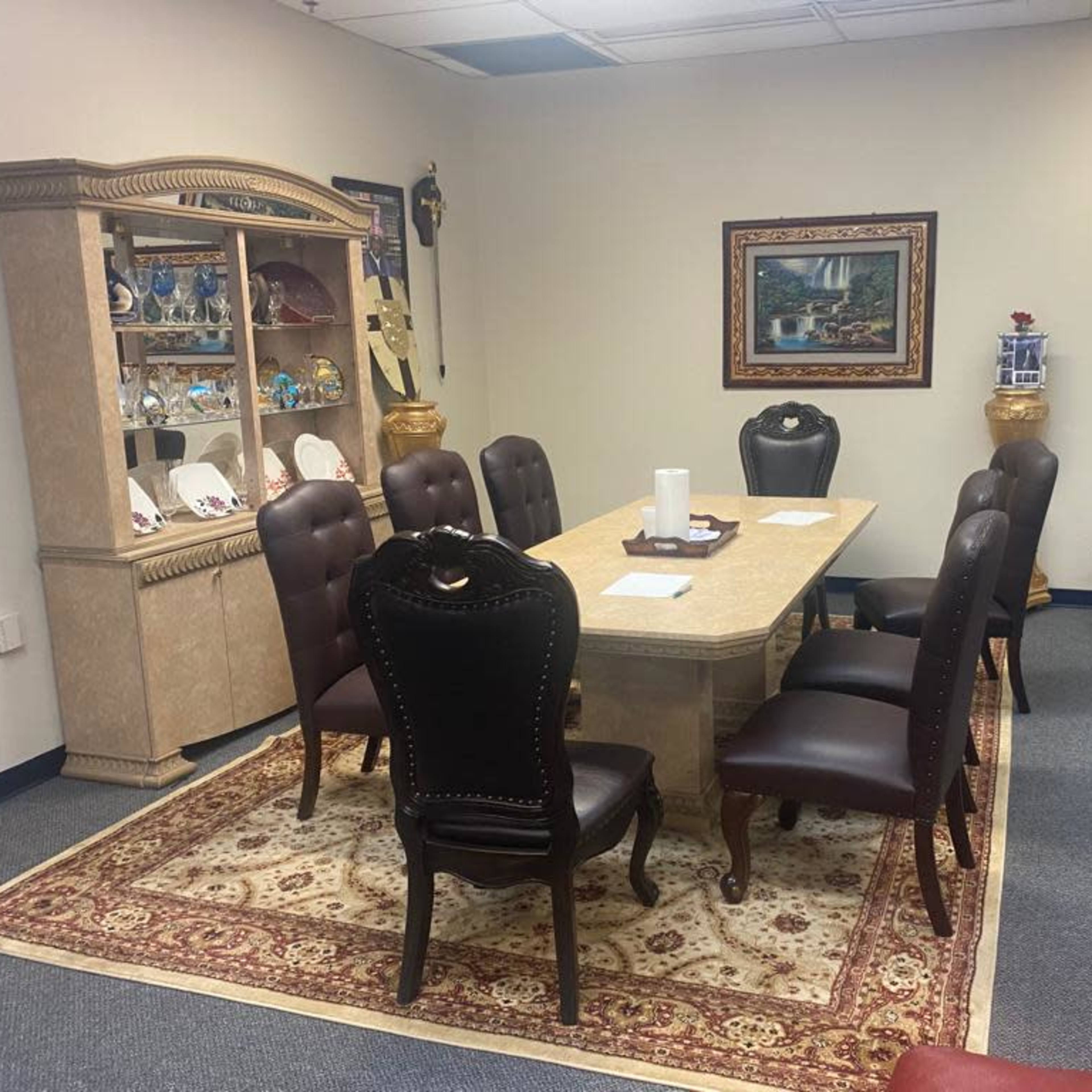 A conference room with a large table surrounded by eight leather chairs, a display cabinet, and decorative wall art.