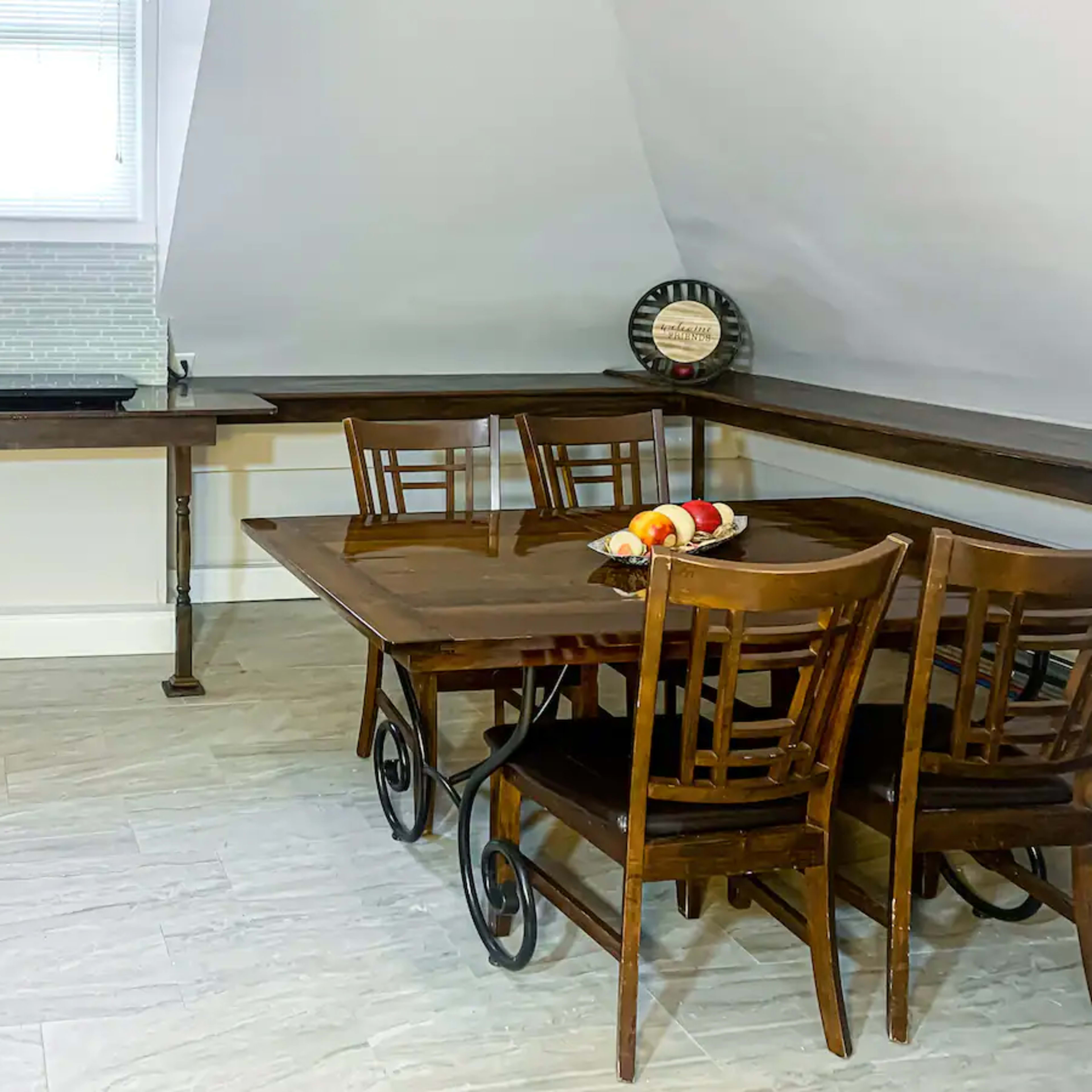A small kitchen area with a dining table and chairs, alongside a counter and various appliances.