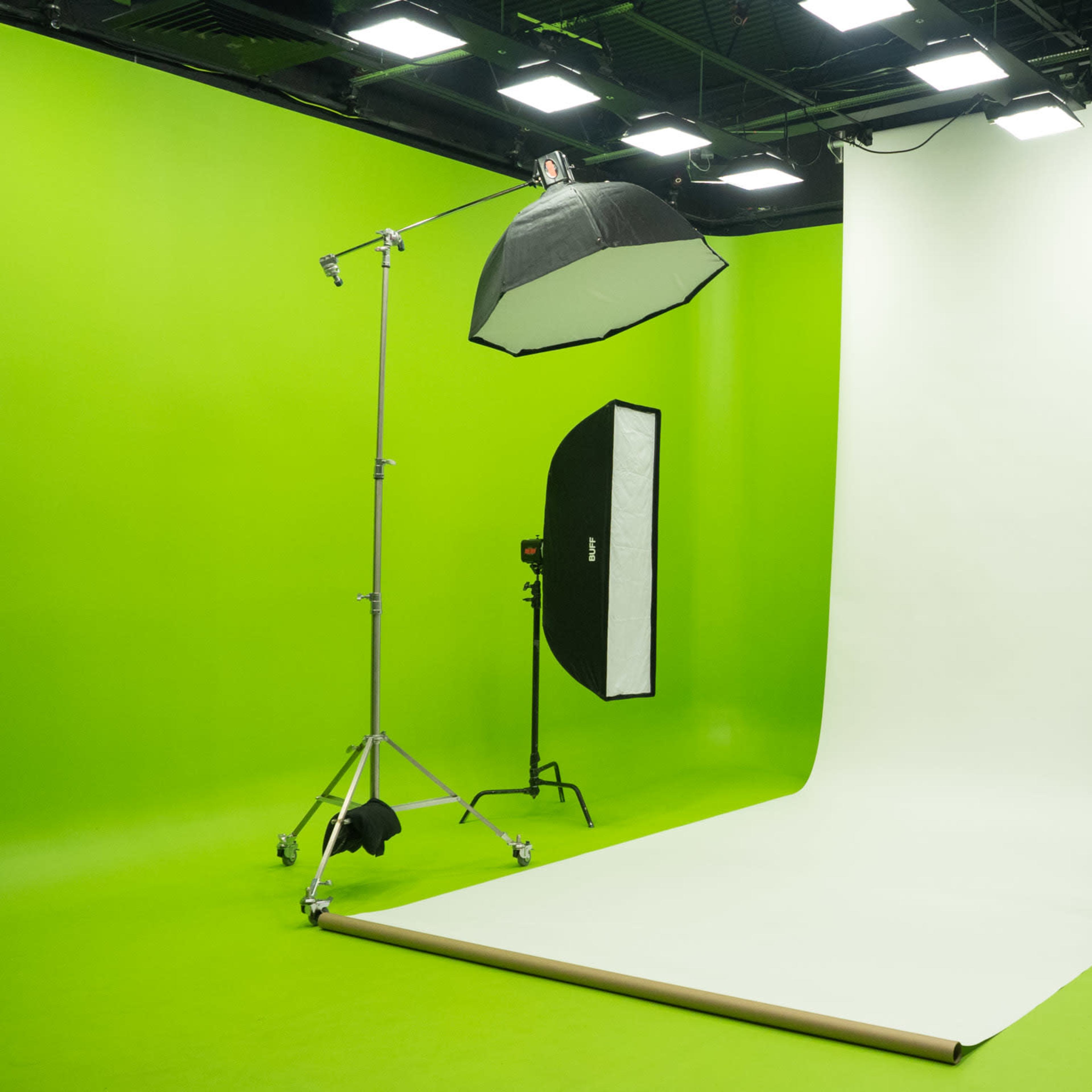 A studio with a large green backdrop and overhead lighting.