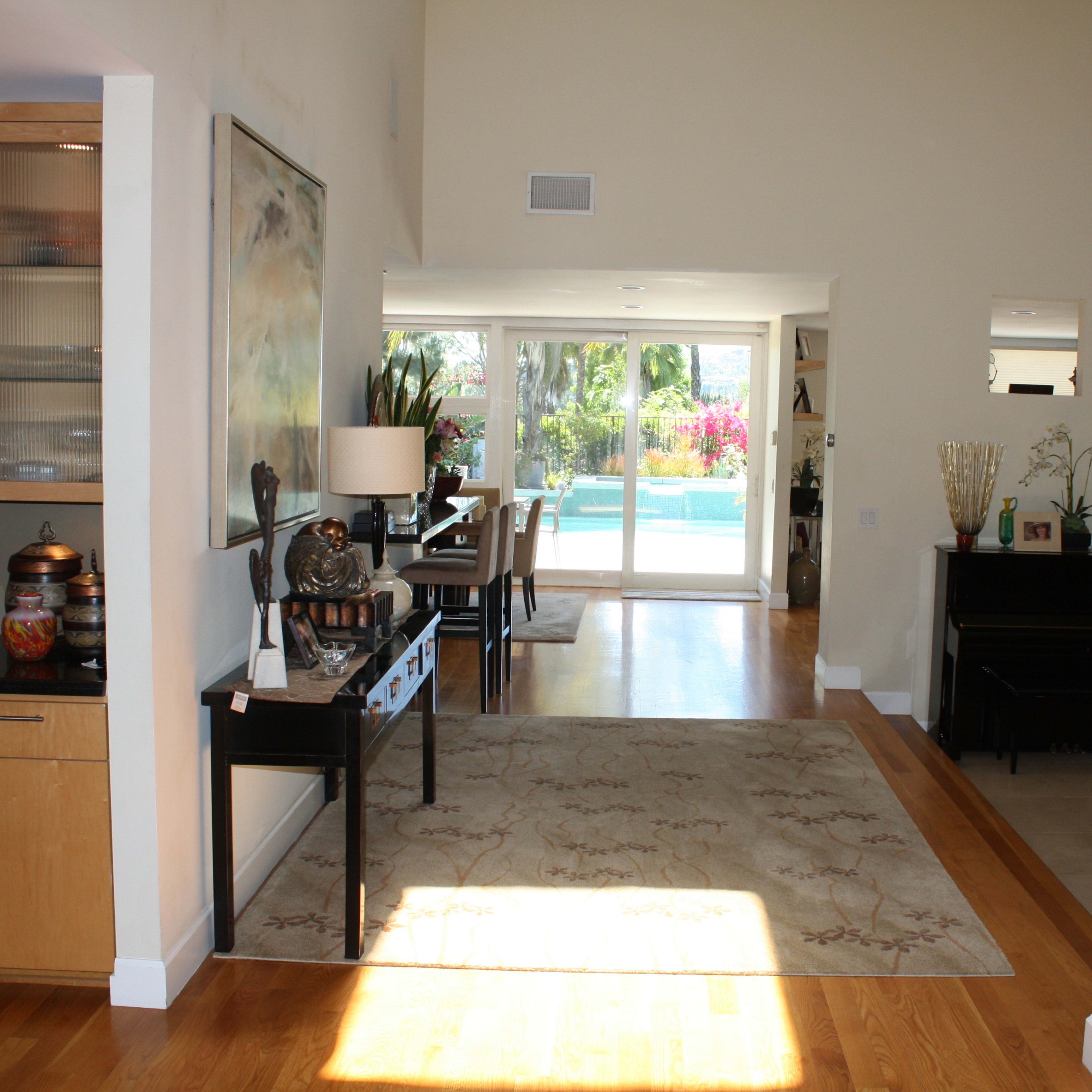 A spacious, bright interior of a home with a view of a pool area through large sliding glass doors.