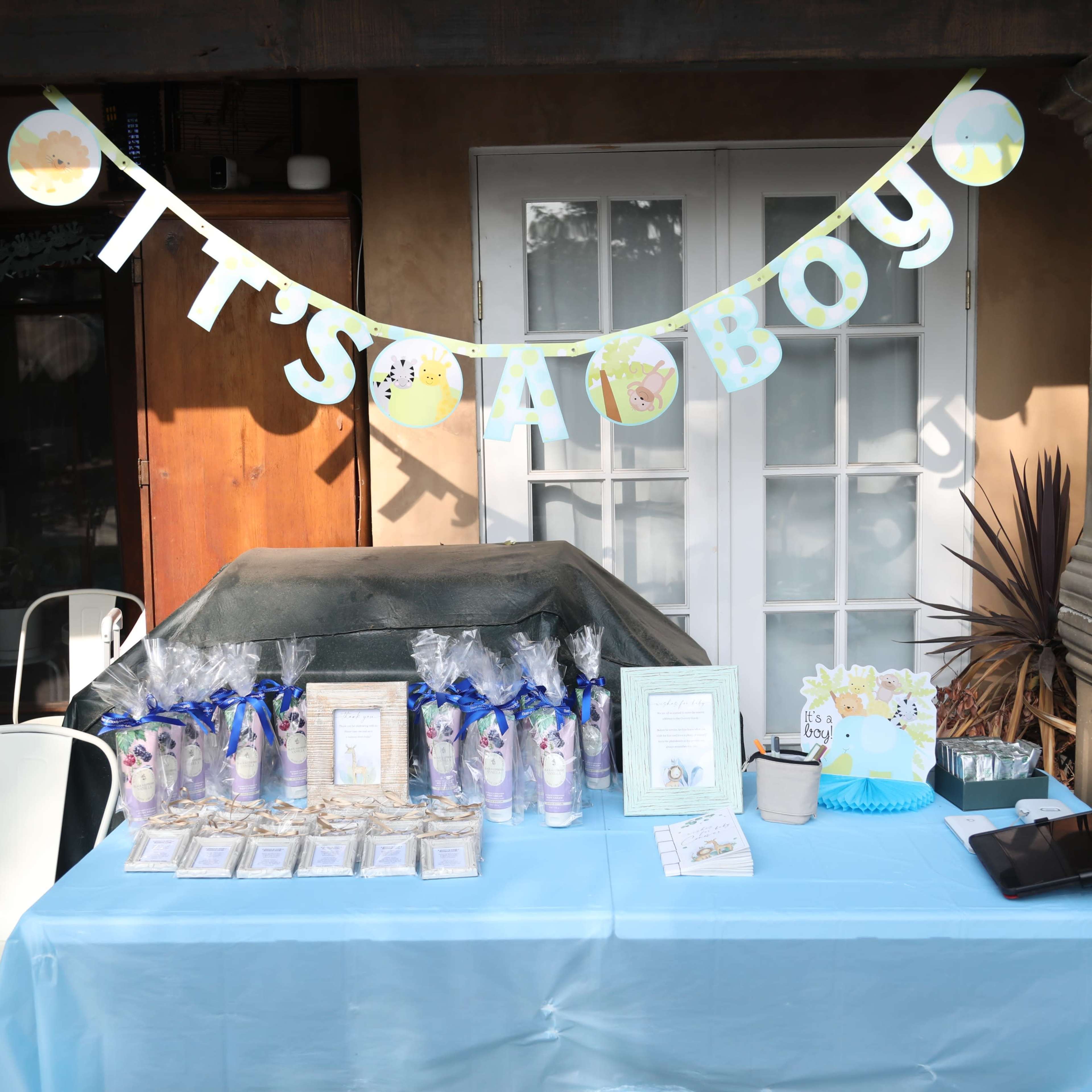 A decorated table showcases party favors and treats with a banner reading "It's a Boy" in a festive setting.