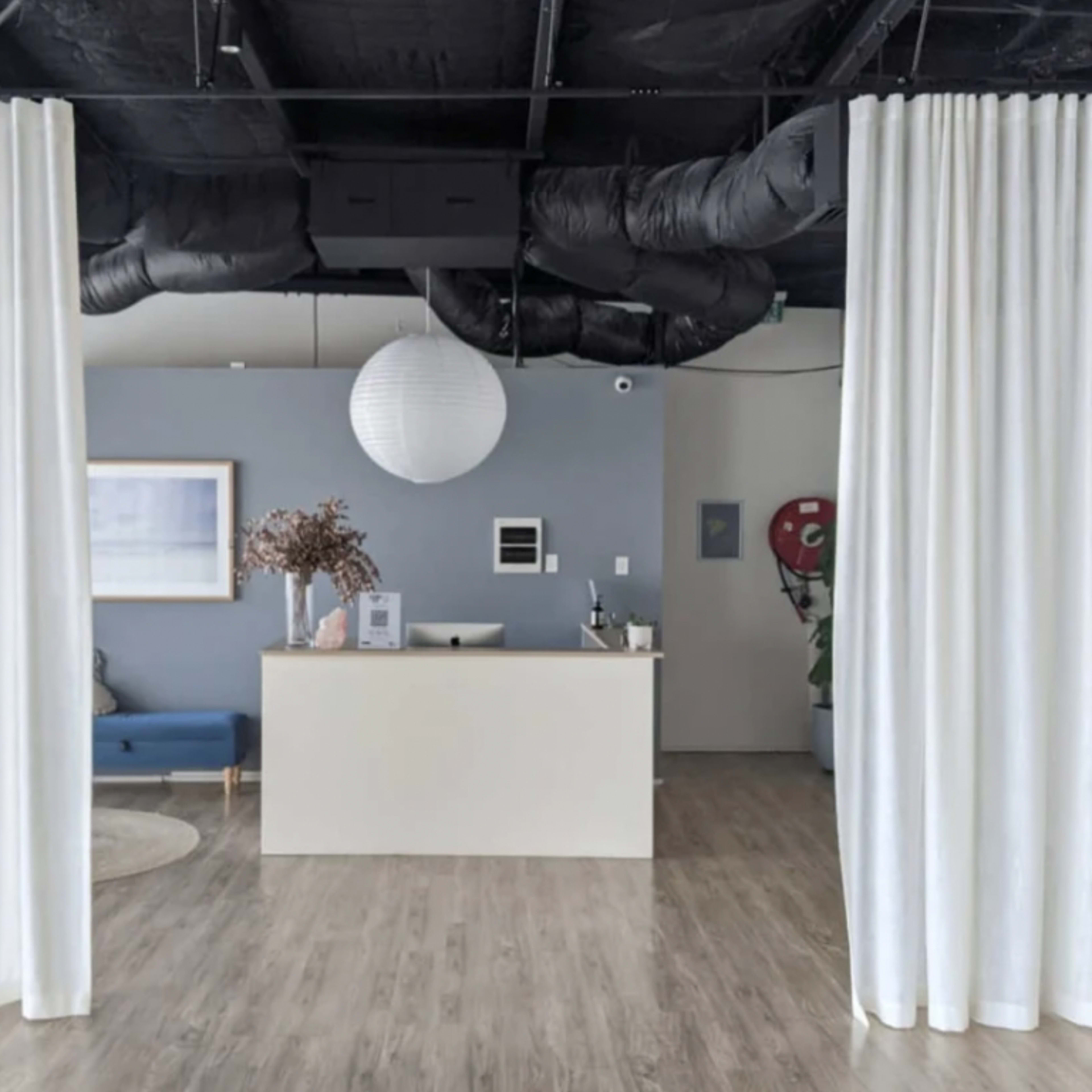A modern reception area with a white countertop, a blue couch, and sheer white curtains separating the space.