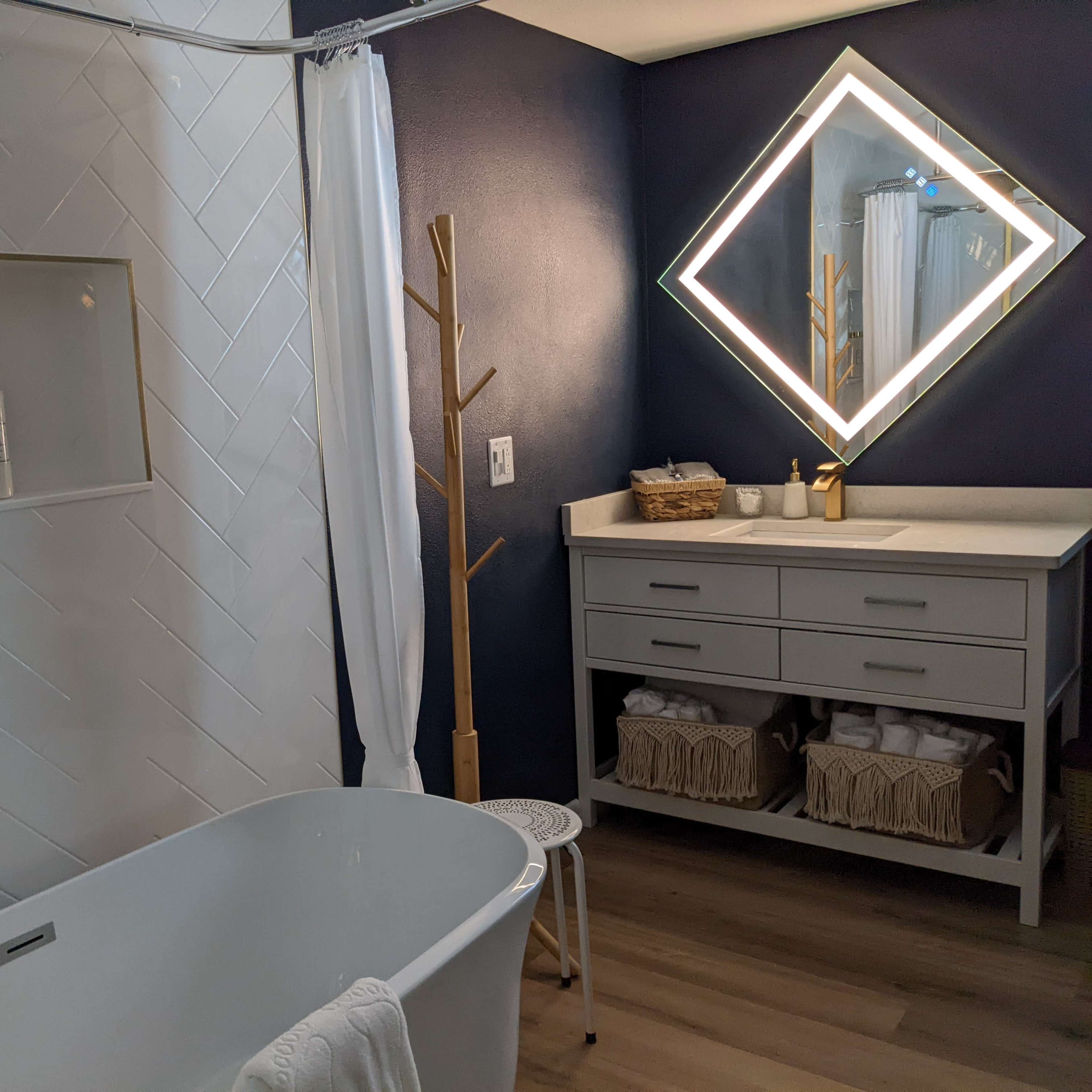 A modern bathroom with a freestanding bathtub, a wall-mounted mirror, and a wooden vanity, complete with towels and toiletries neatly arranged.