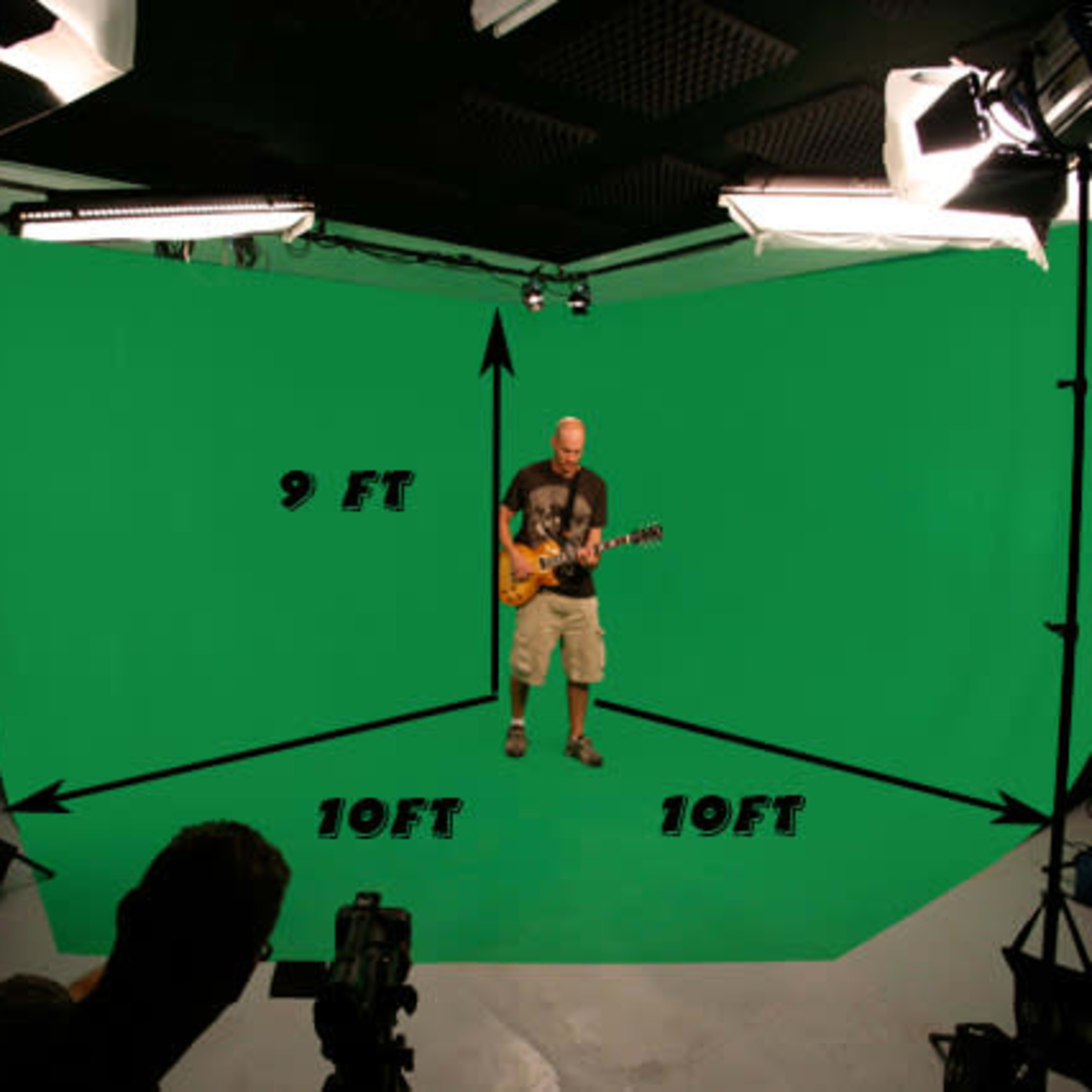 A musician stands on a stage in front of a green screen, with studio lights positioned around him in a 10-foot by 9-foot space.