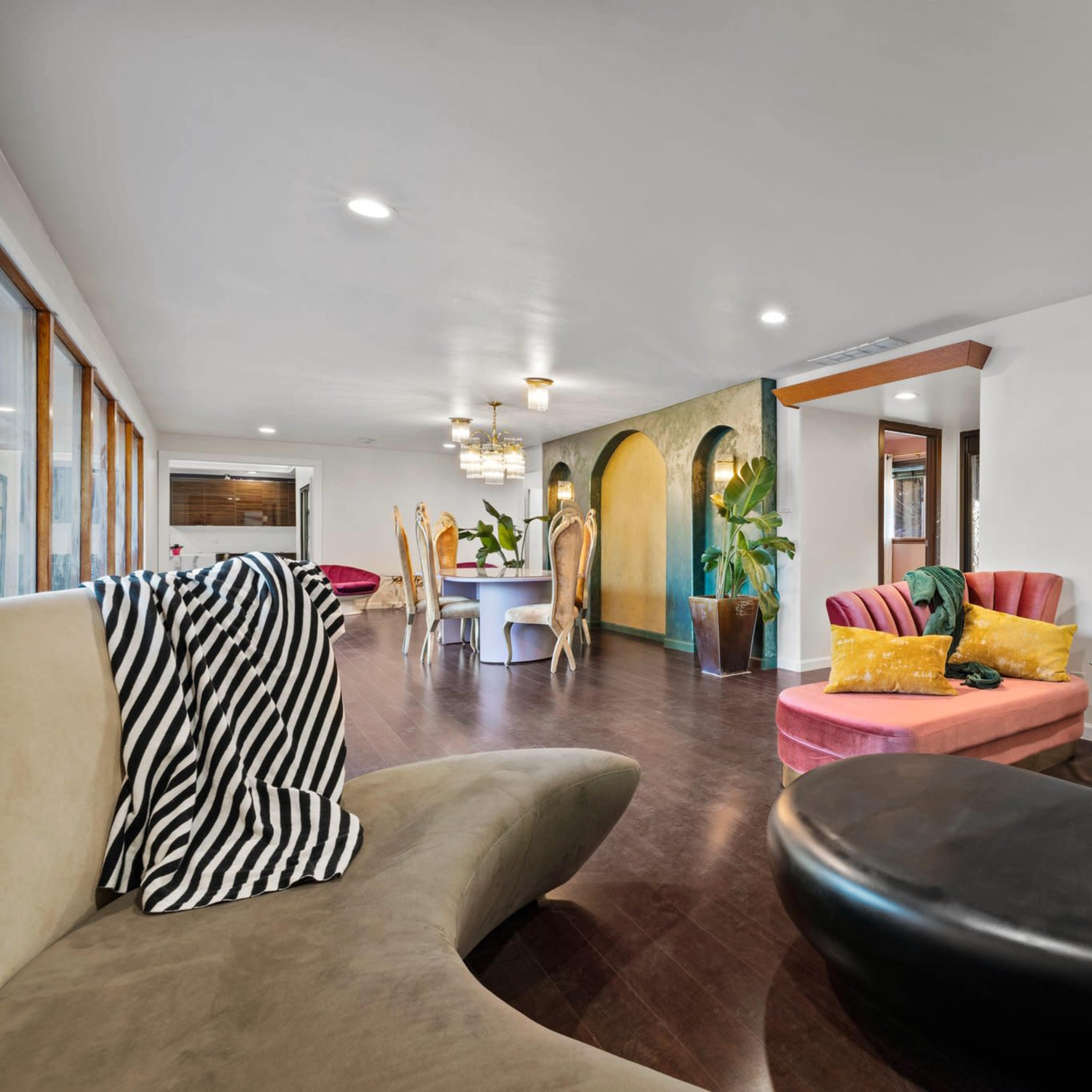 A modern, open-concept living area featuring a mix of seating options and dining spaces, with large windows allowing natural light to fill the room.