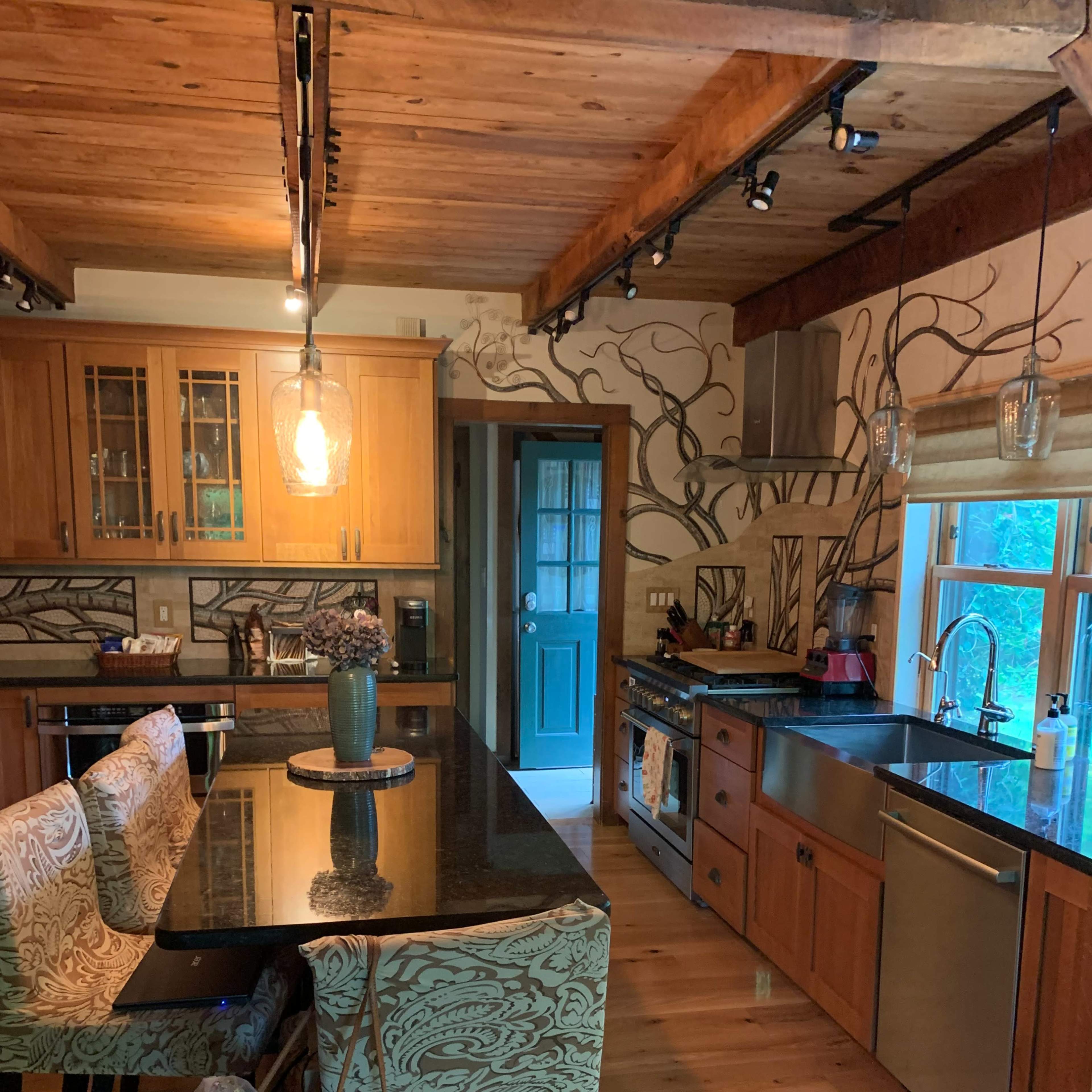 A wooden kitchen with a large island featuring patterned bar stools, modern appliances, and decorative wall art.