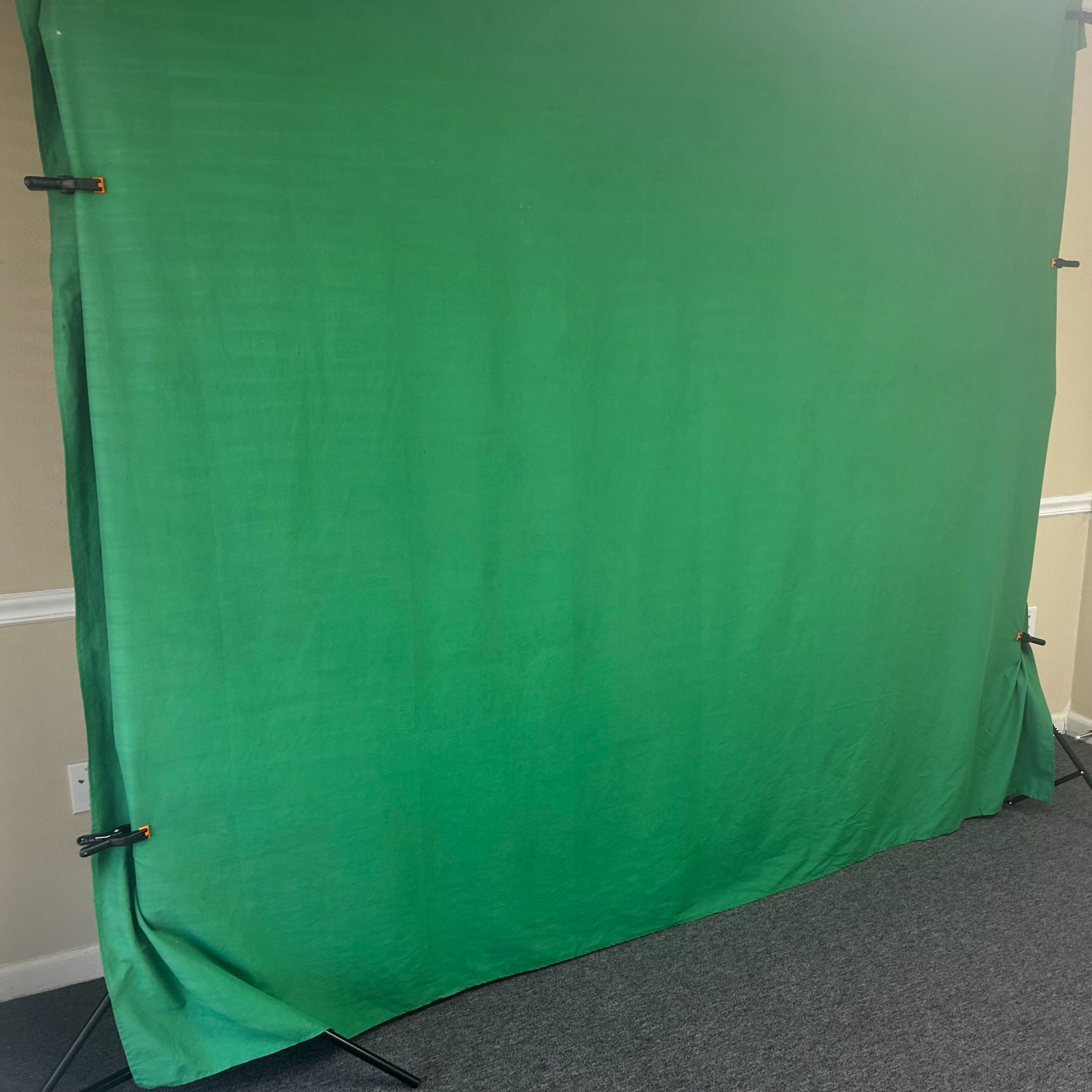 A green backdrop is set up in a room with beige walls and gray carpet.