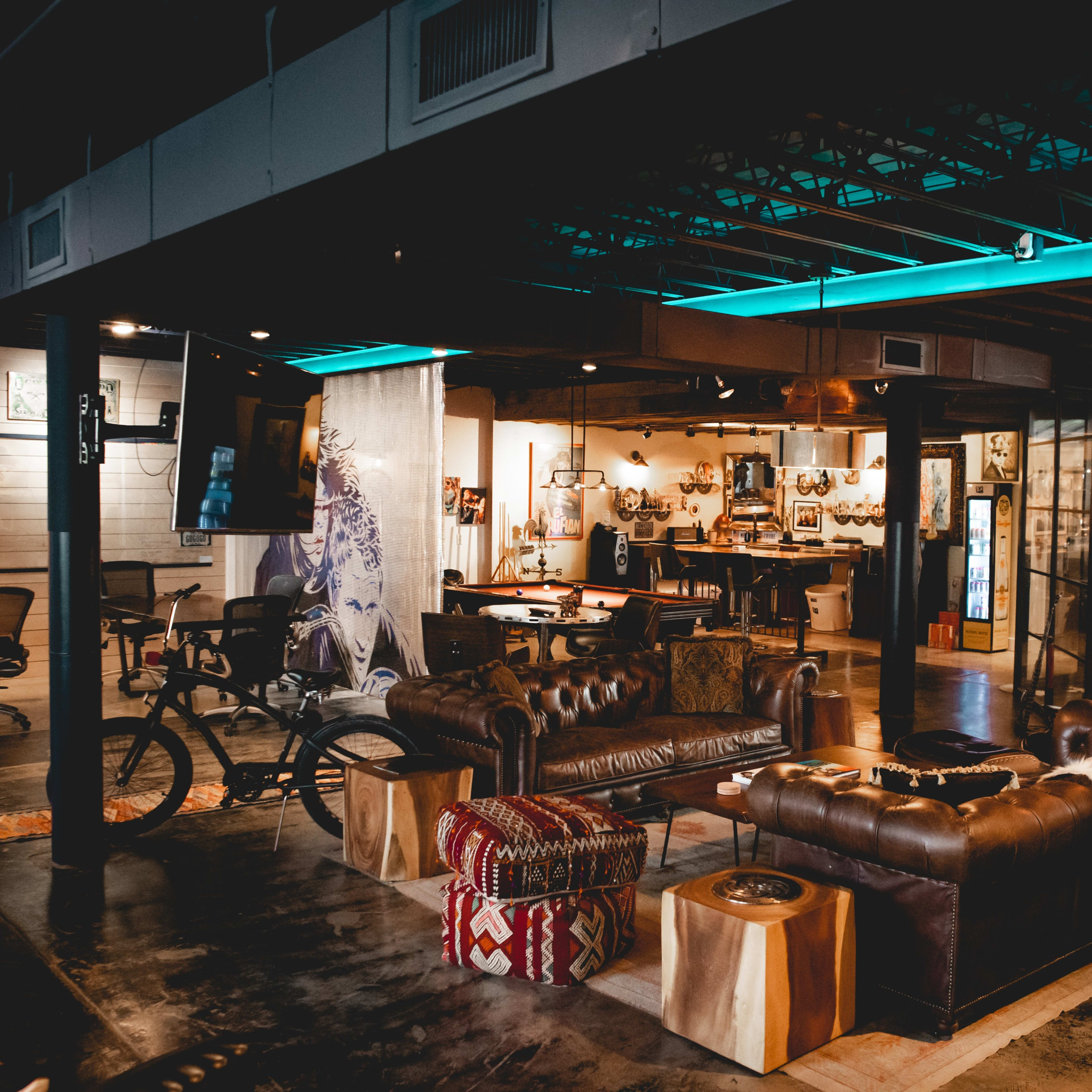 A modern office space featuring leather sofas, a wooden table, and a neon sign that reads "Jake's."