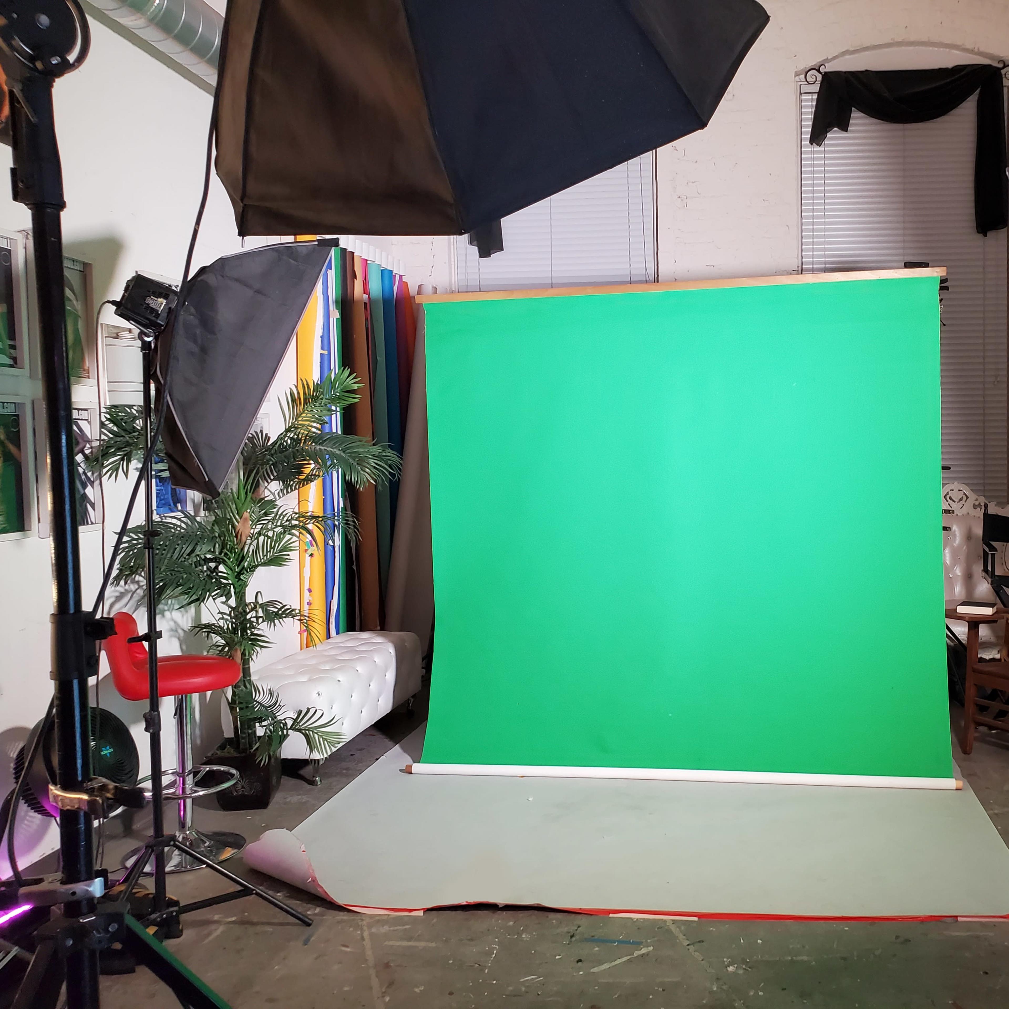 A photography studio setup with a green backdrop, lighting equipment, and various accessories arranged around the space.
