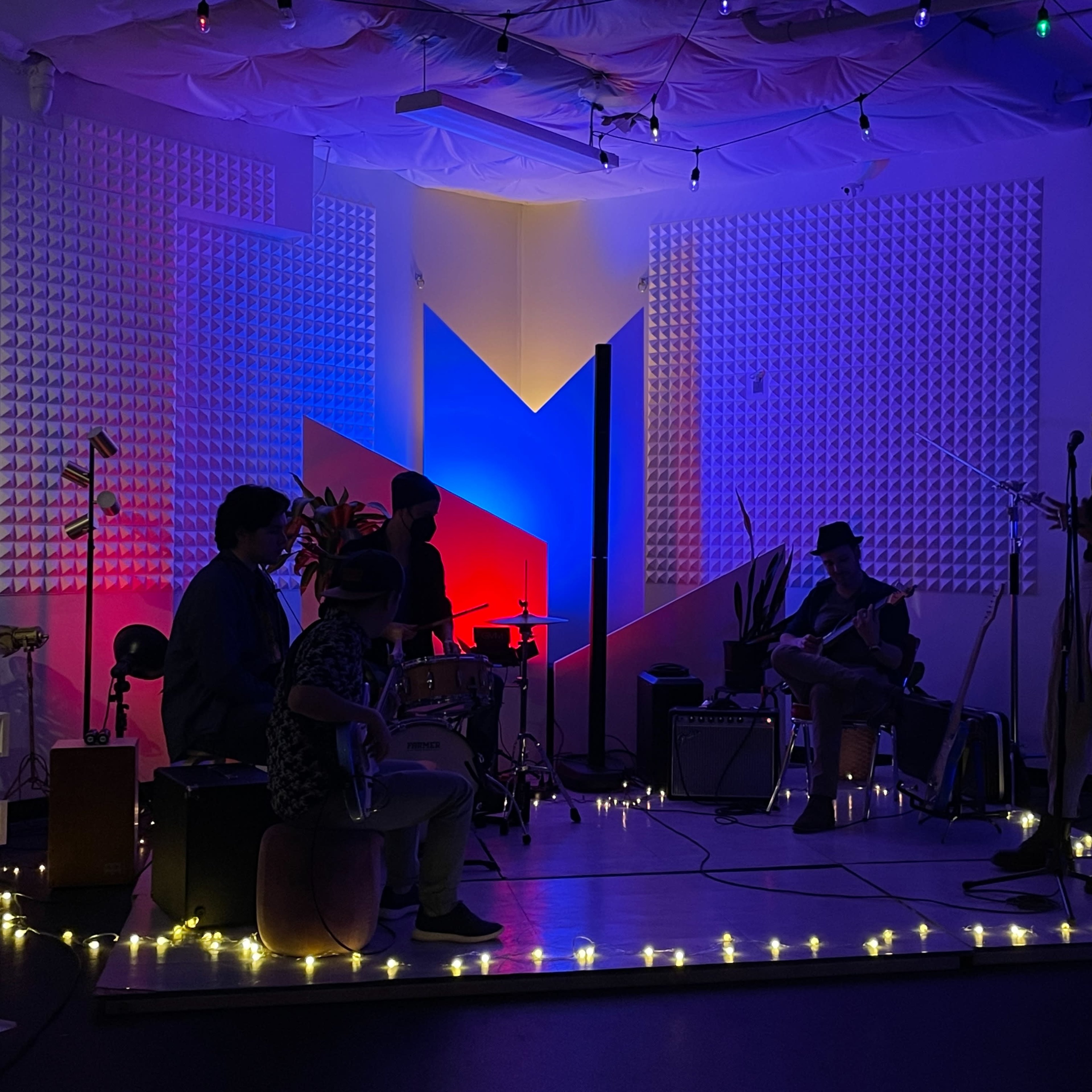 A band performs on a small stage adorned with colorful lights and ambient decorations.